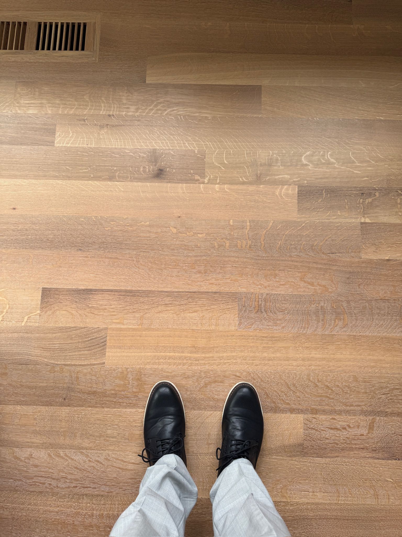 A person wearing black boots is standing on a wooden floor.
