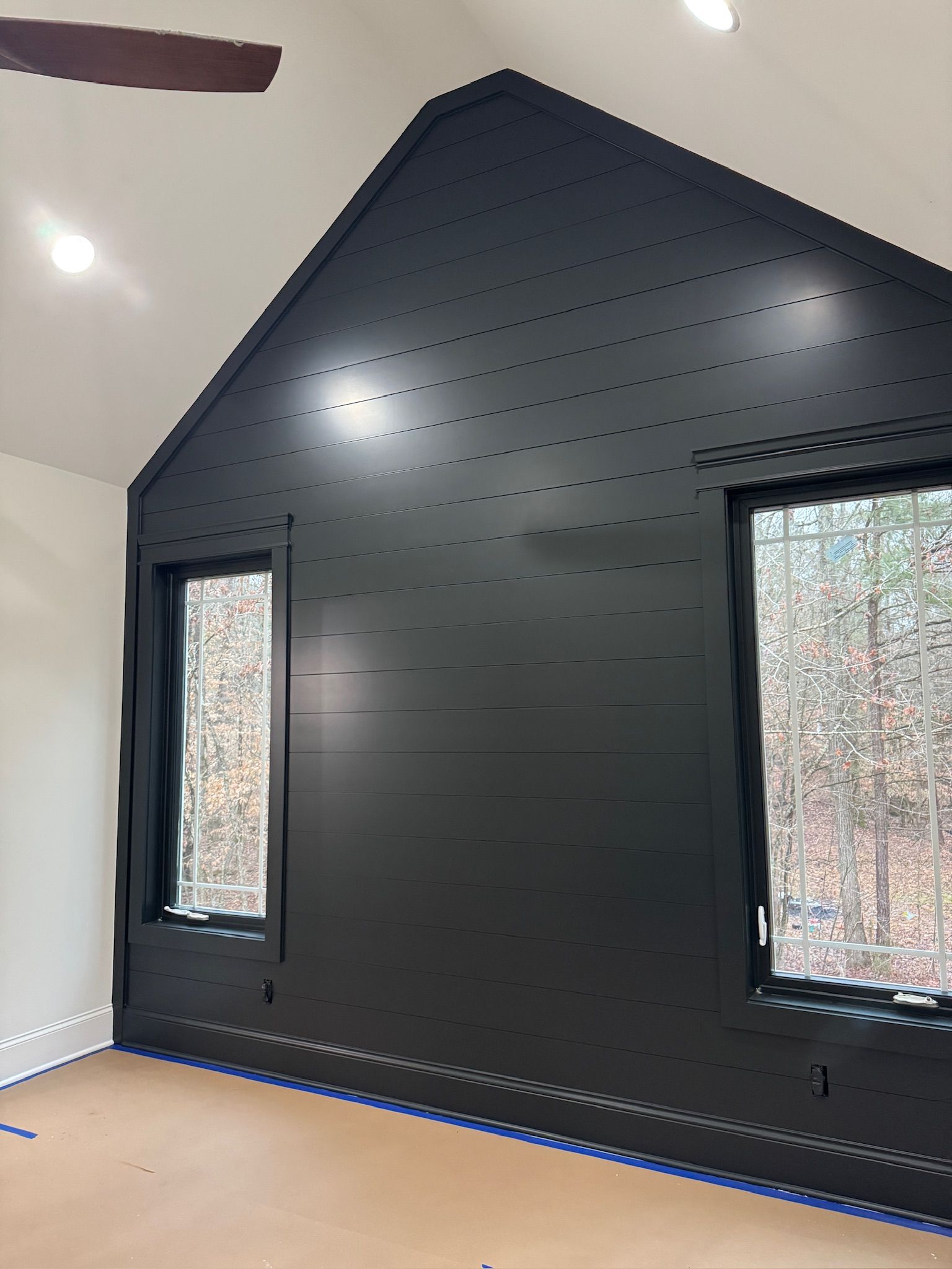 A room with a black wall and two windows