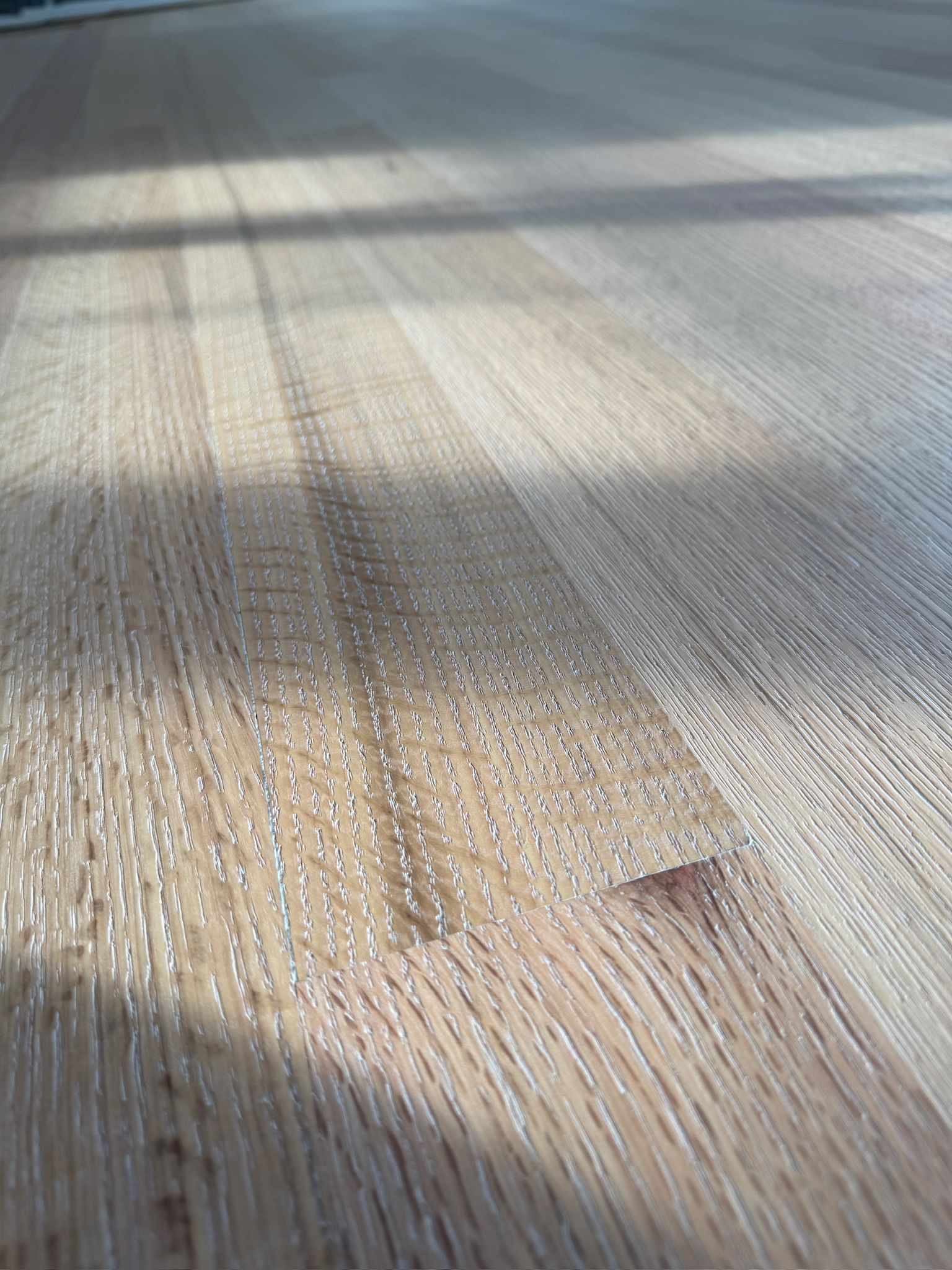 A close up of a wooden floor with a shadow on it.