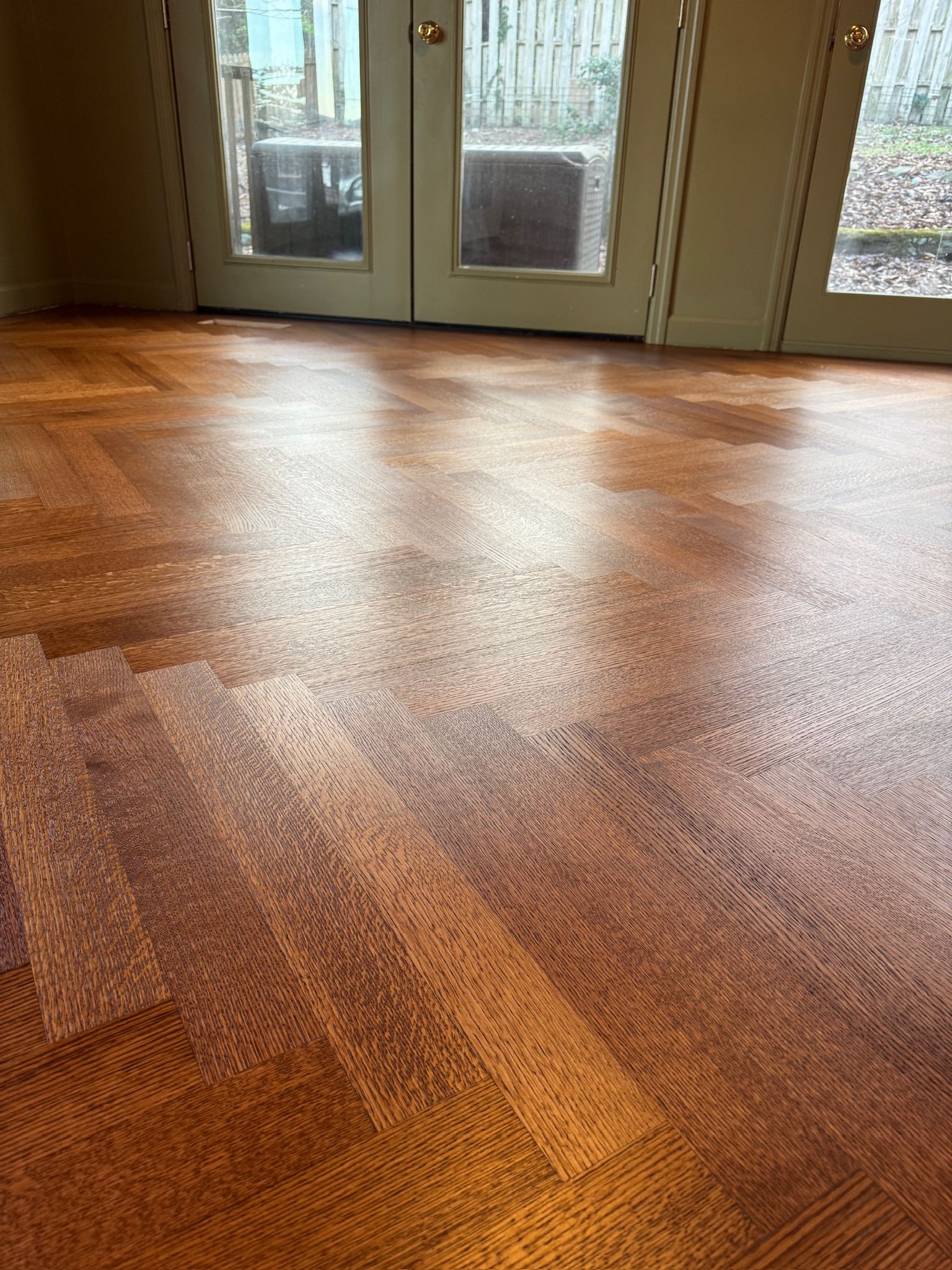 A close up of a wooden floor in a room with sliding glass doors.