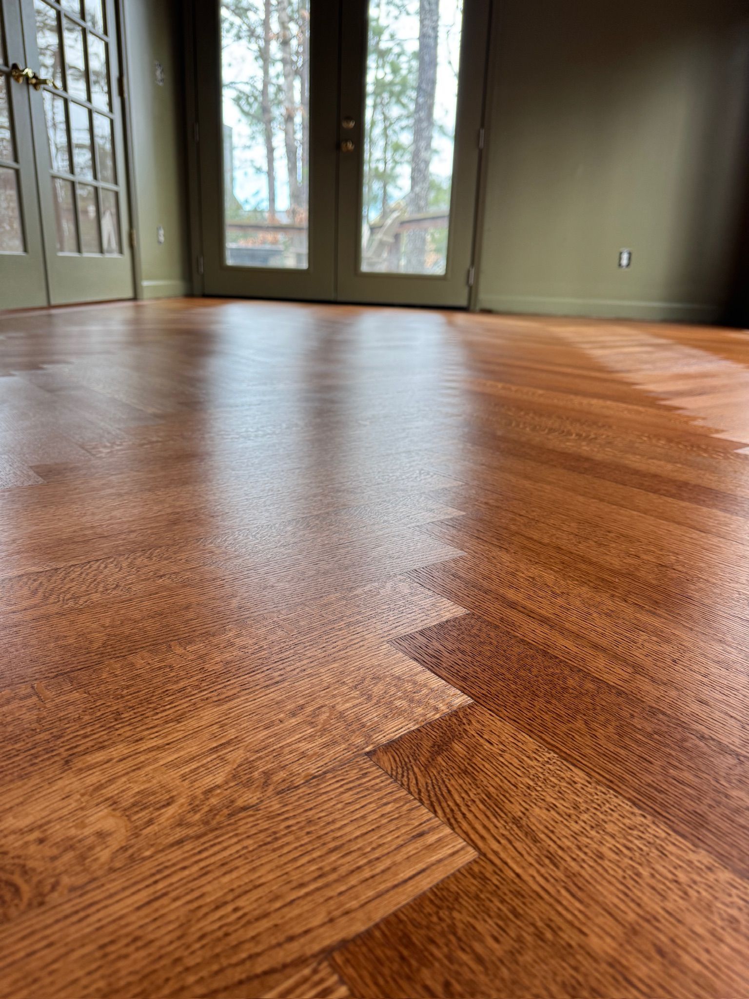 A close up of a wooden floor in a room with sliding glass doors.