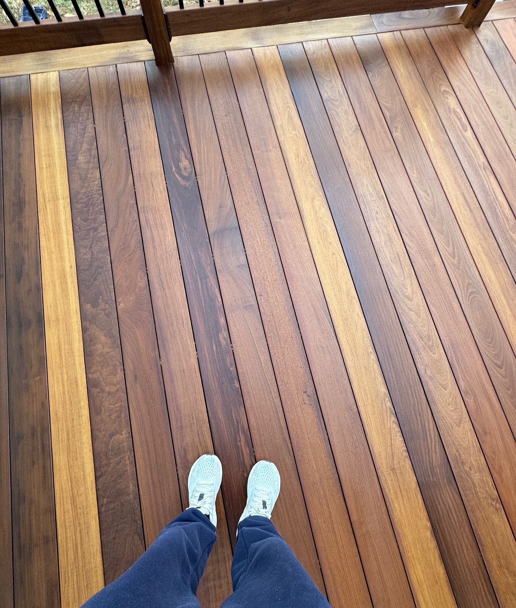 A person 's feet are standing on a wooden deck