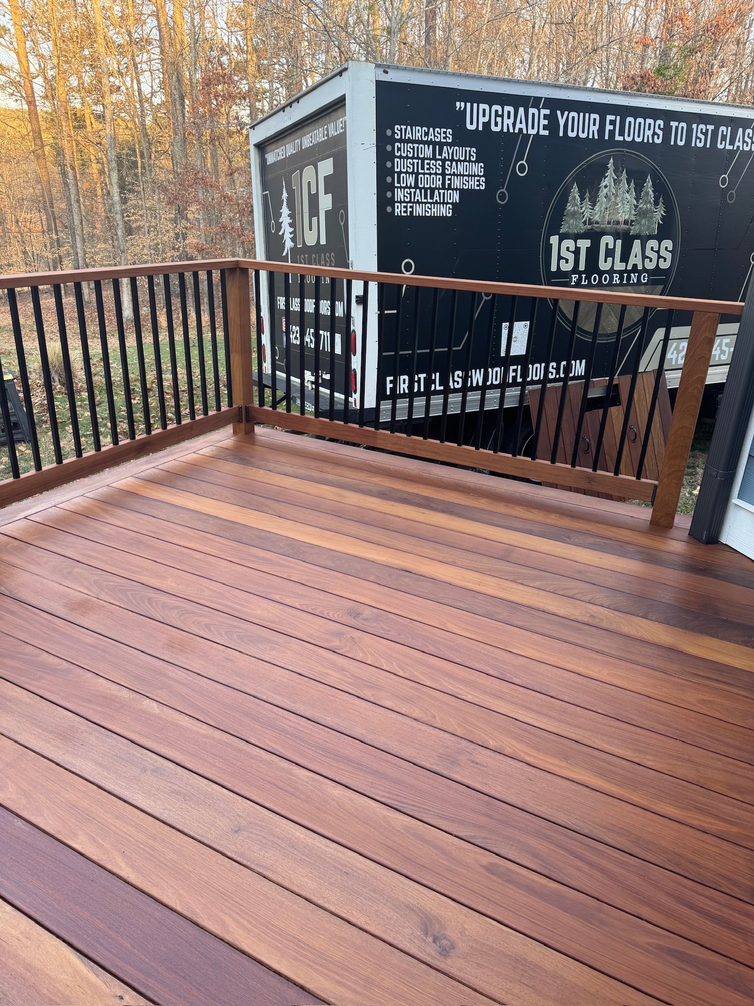 A wooden deck with a metal railing and a truck in the background.