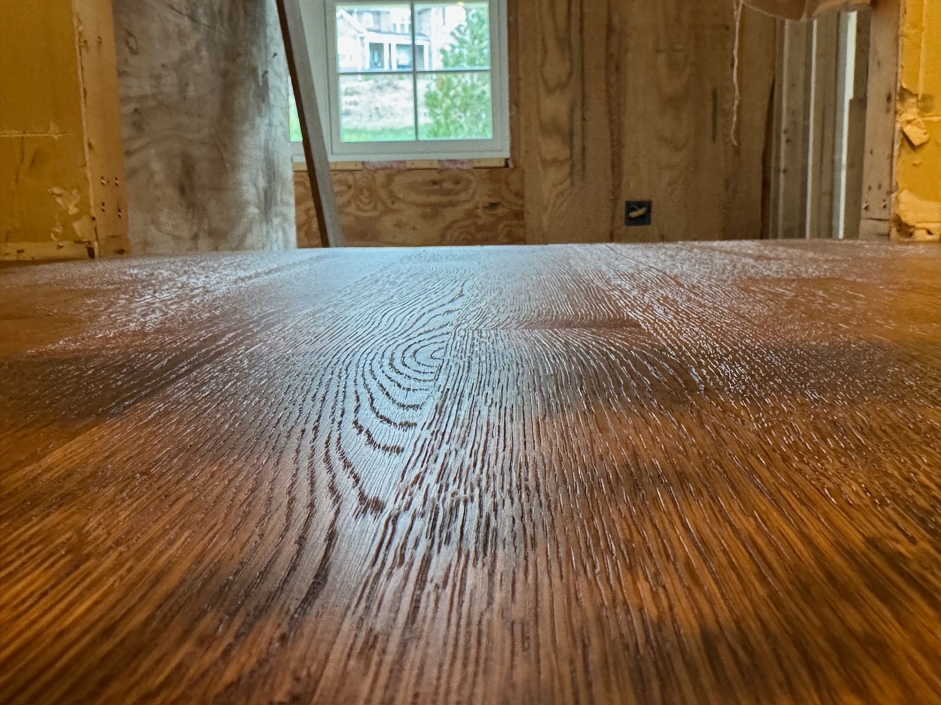 A close up of a wooden table with a window in the background.