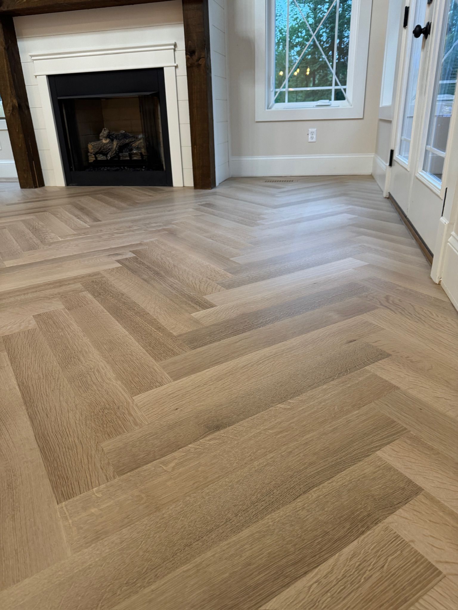 A living room with a fireplace and a herringbone floor.