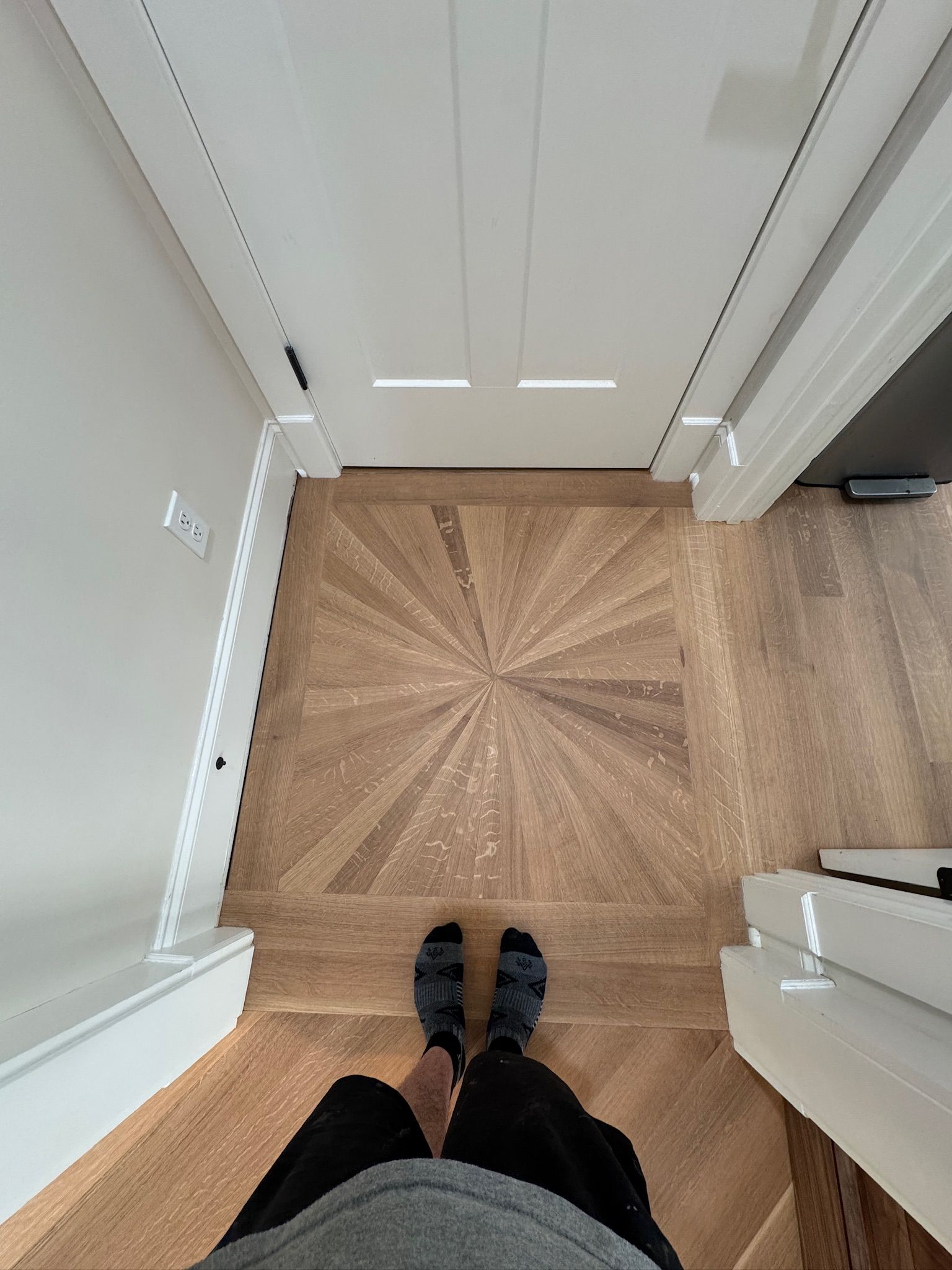A person is standing on a wooden floor in a hallway.