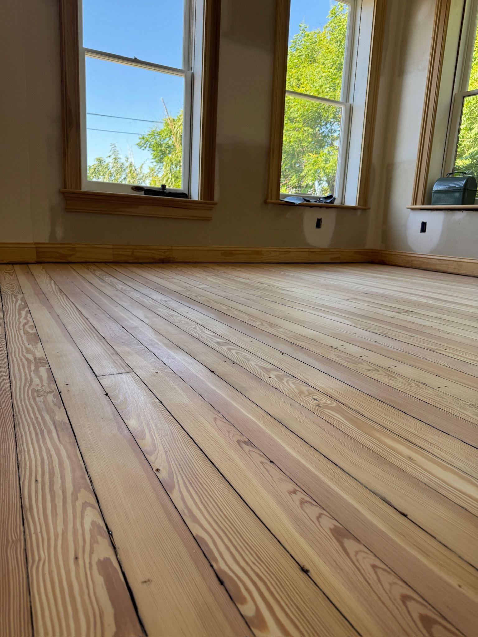 A room with a wooden floor and two windows.