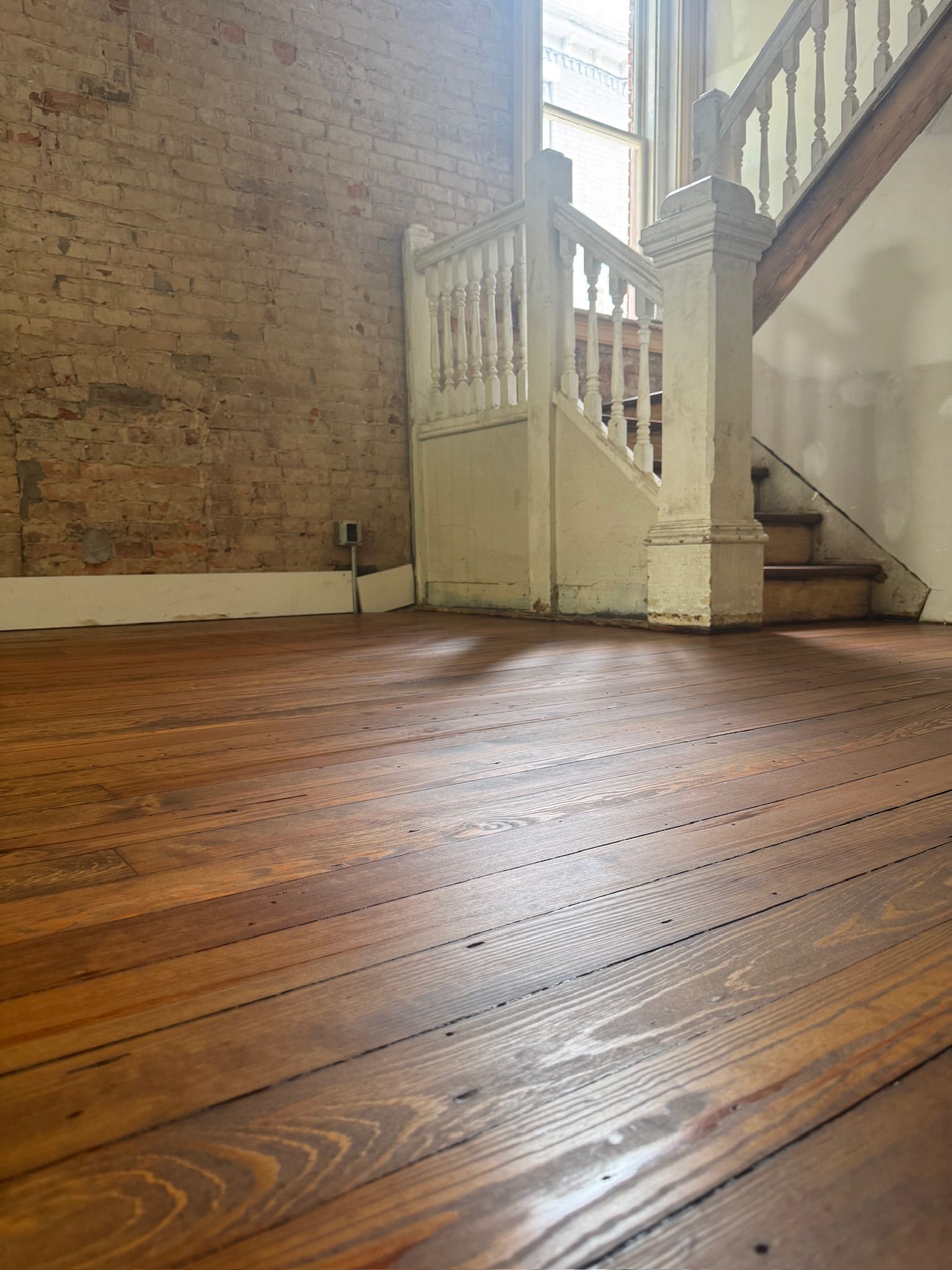 An empty room with a wooden floor and stairs.