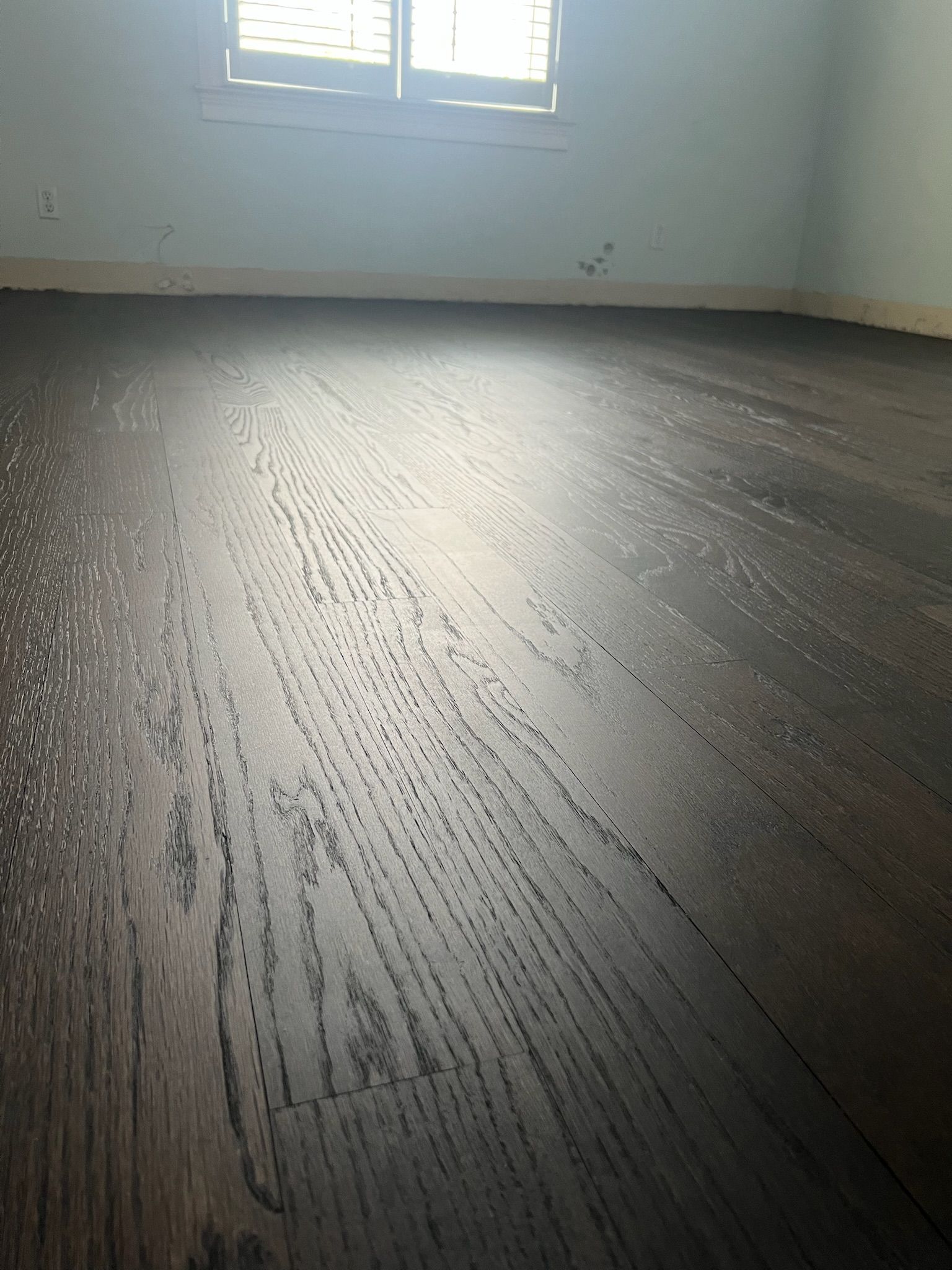 A dark wooden floor in a room with a window