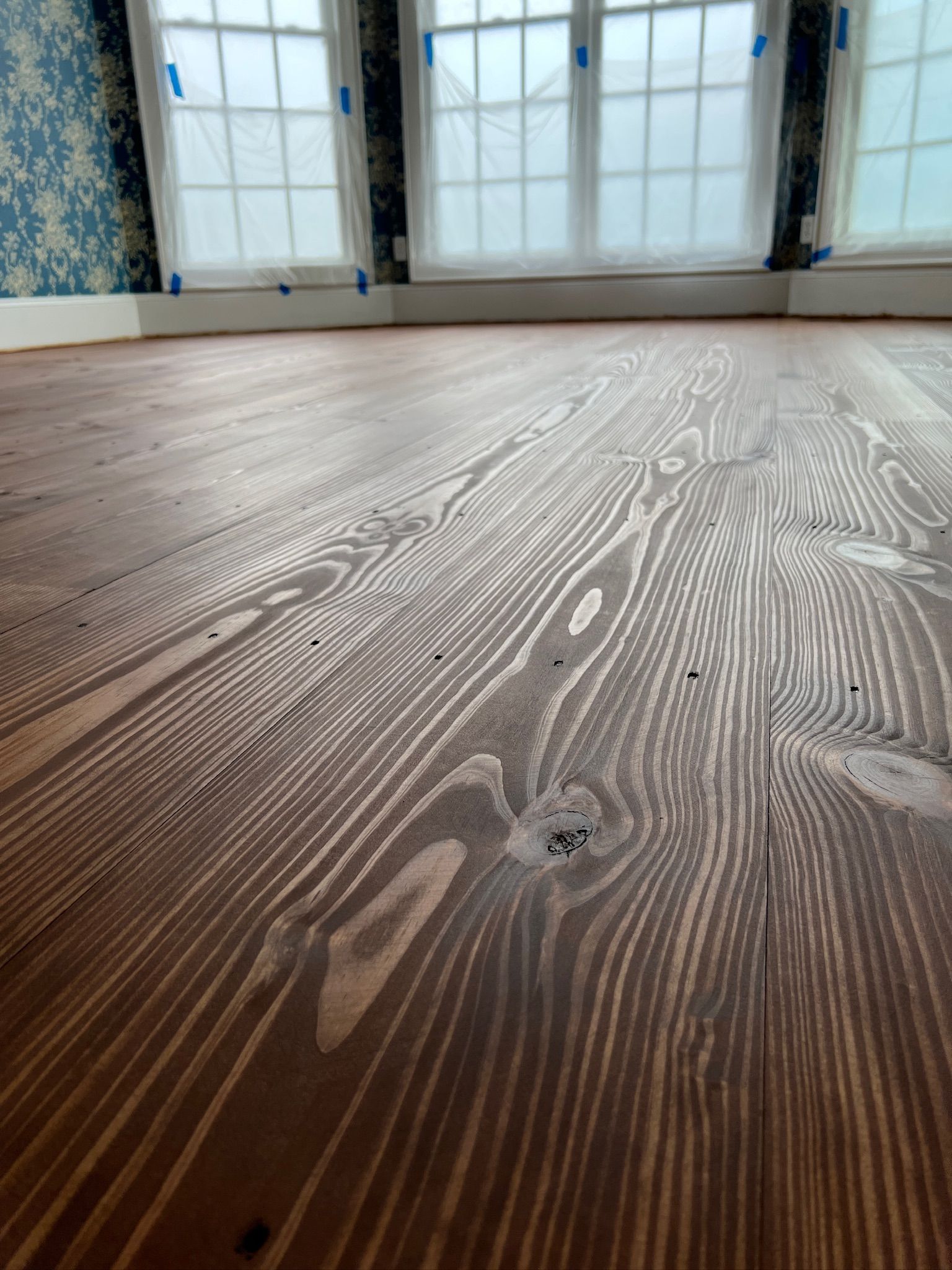 A close up of a wooden floor in a room with windows.