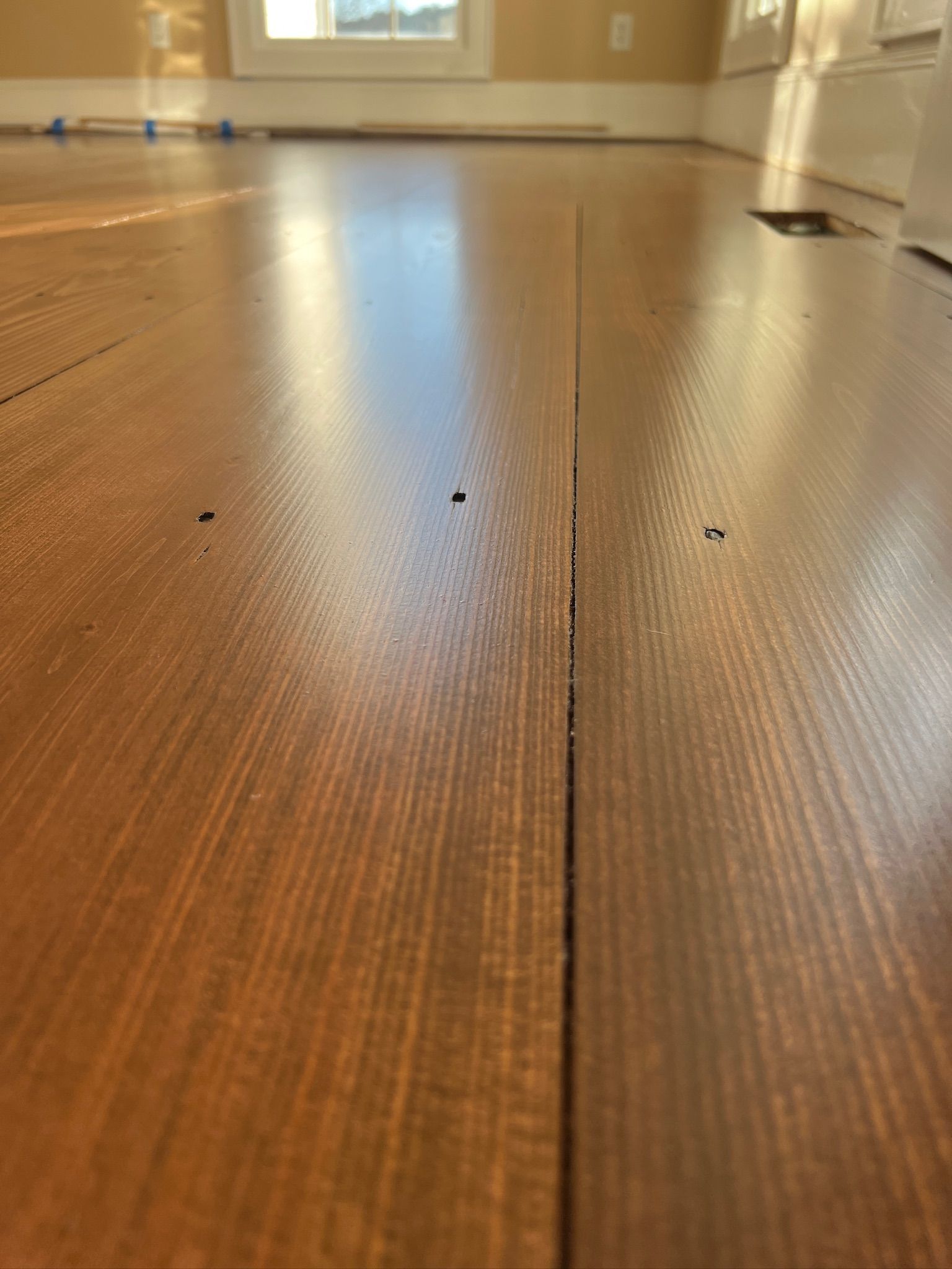 A close up of a wooden floor in a room with a window.