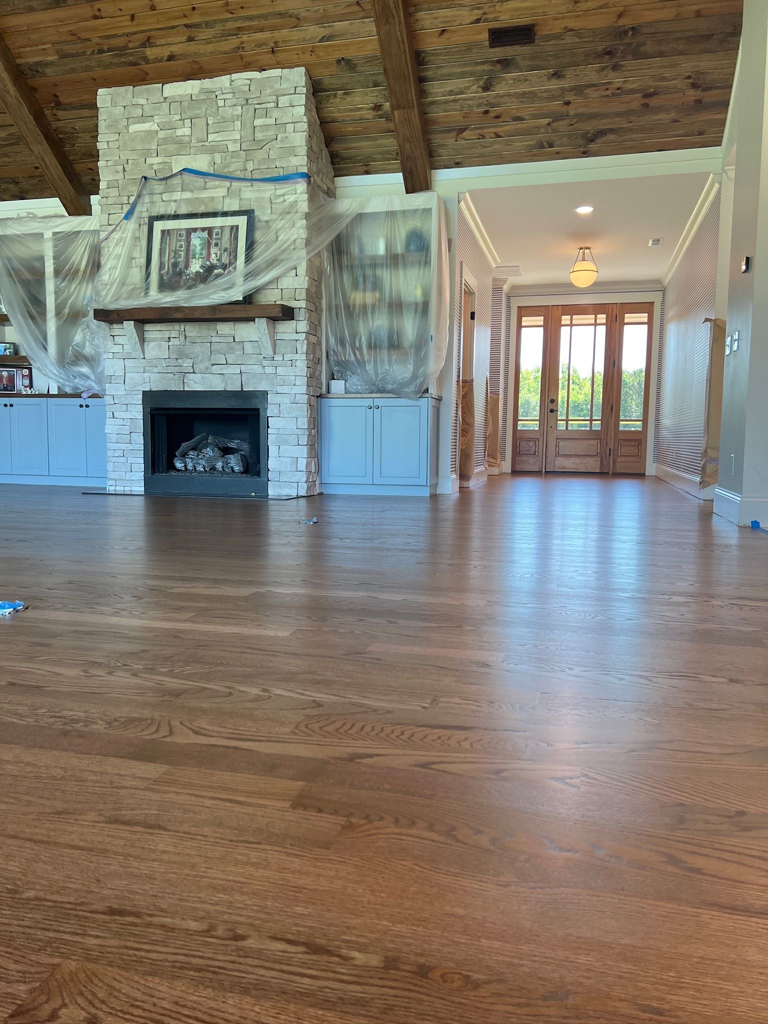 A living room with hardwood floors and a stone fireplace.