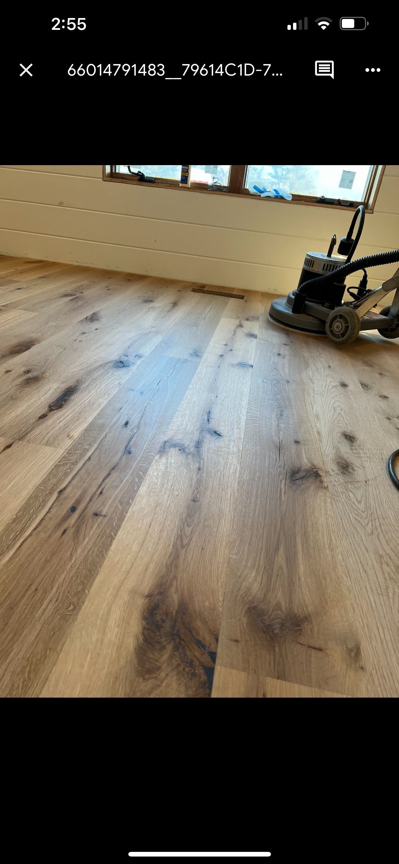 A wooden floor is being sanded with a machine.