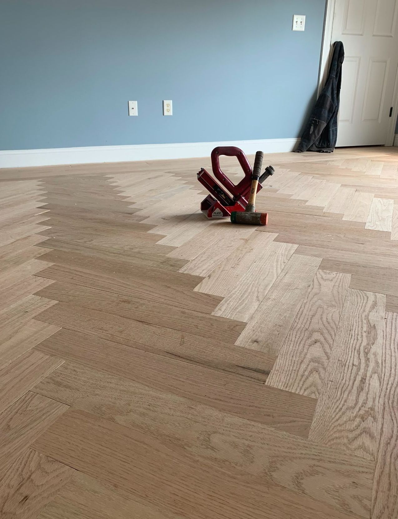 A red tool is sitting on a wooden floor in a room.