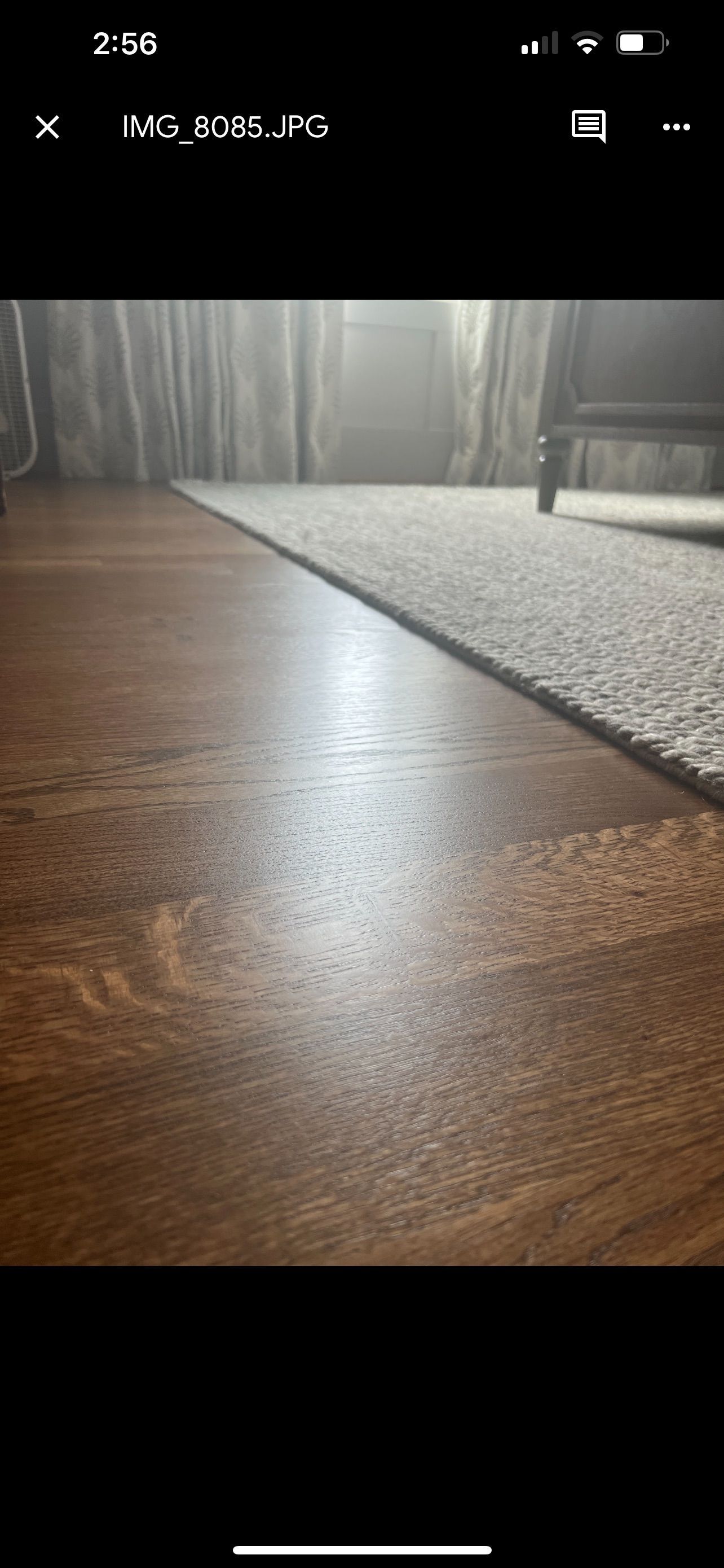 A wooden floor next to a white carpet in a living room.