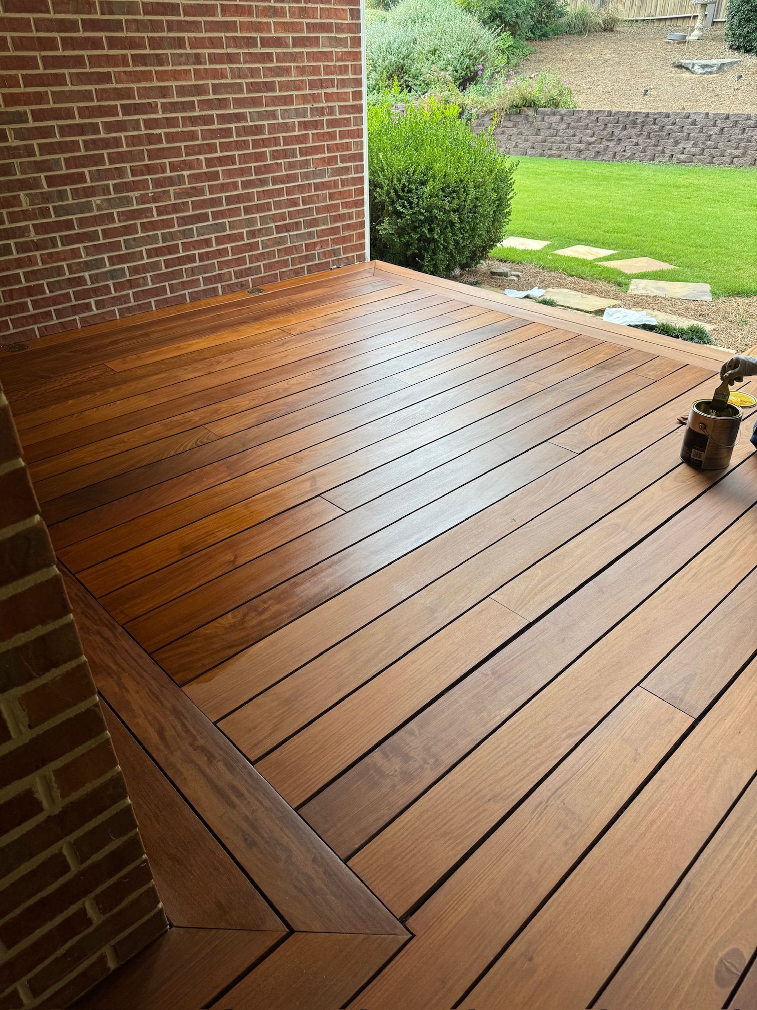 A wooden deck with a brick wall in the background