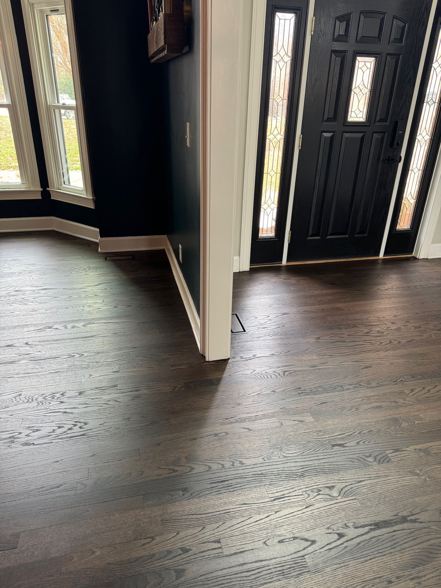 A living room with hardwood floors and a black door.