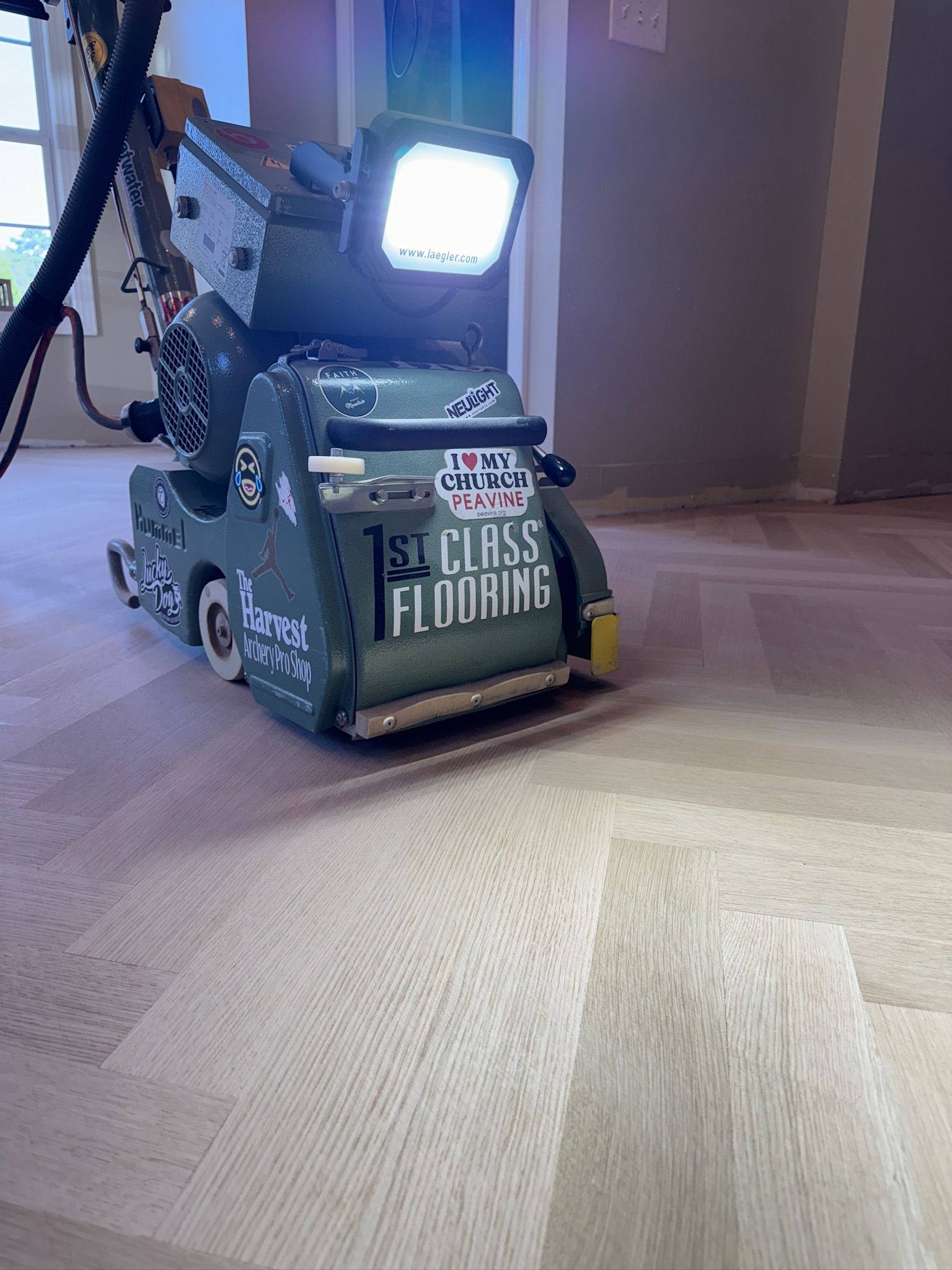 A machine is sanding a wooden floor in a room.