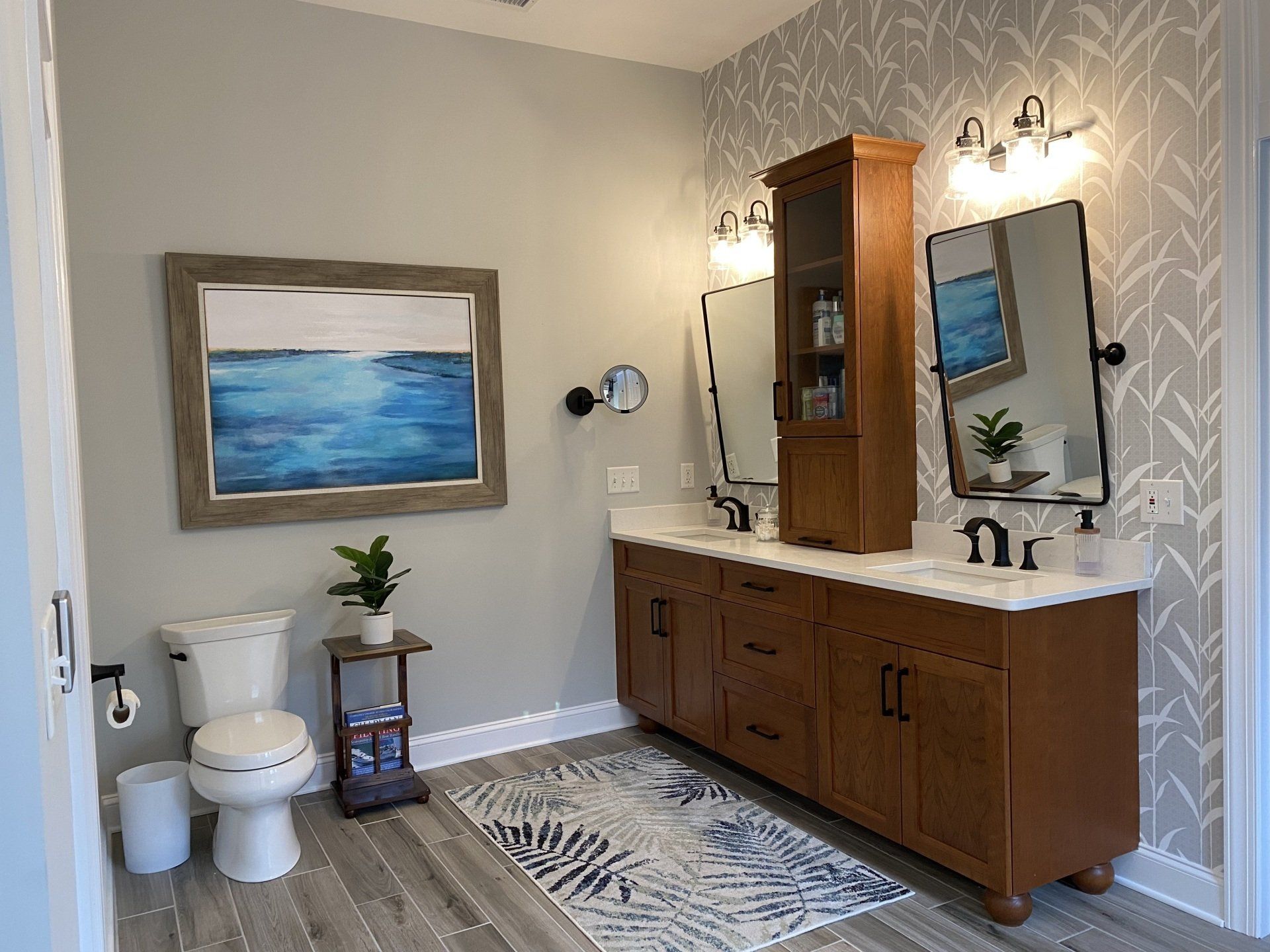 Bathroom with cherry wood double bathroom vanity with furniture ball feet and floral, grey wallpaper.