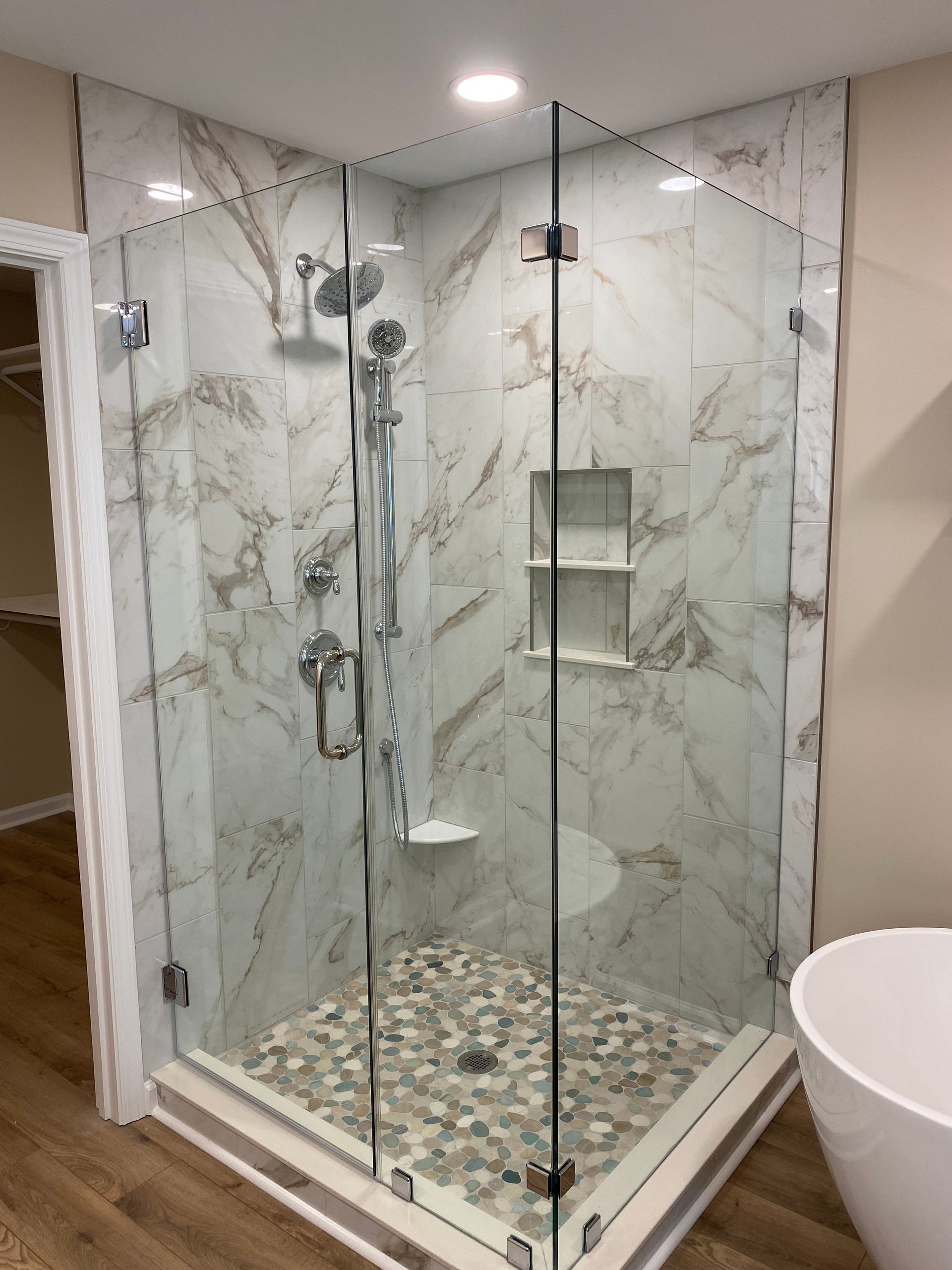 Walk-in tiled shower with chrome fixtures and custom wall niche.