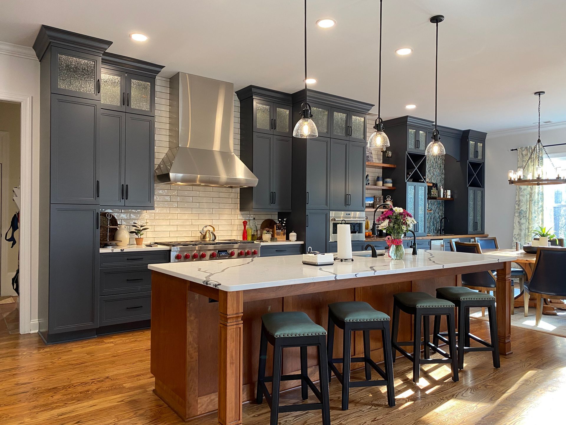 Kitchen remodel featuring dark blue cabinets, accented rain glass stacked cabinets, and large island with bar stools.