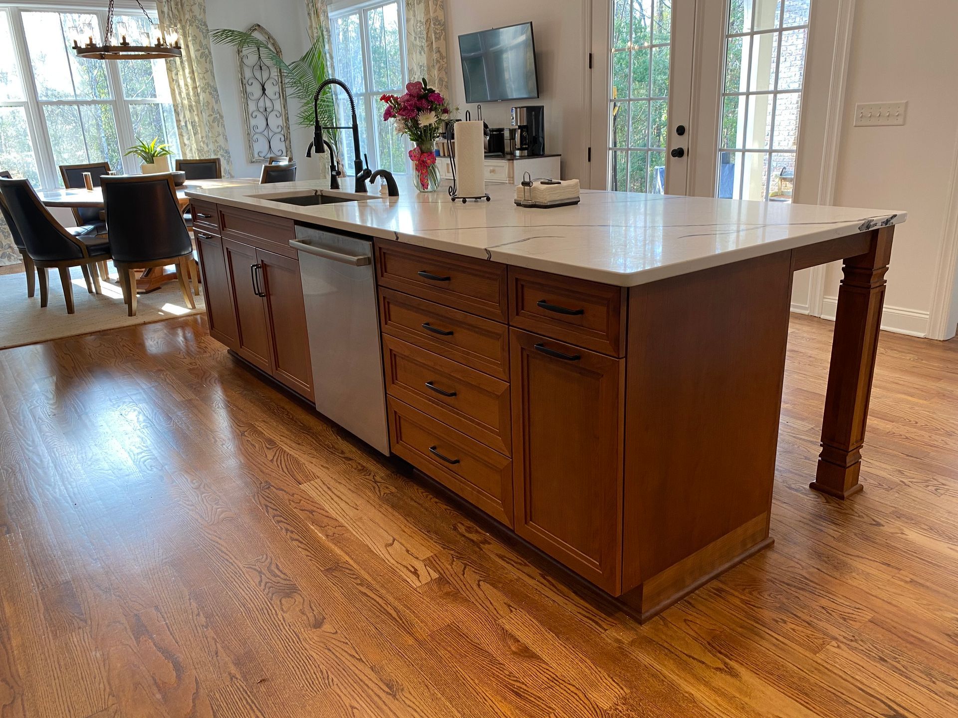 Large clear cherry kitchen island with sink and black faucet.