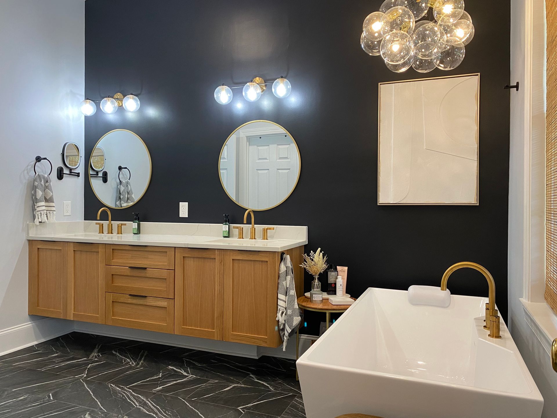 Modern bathroom remodel with black walls and gold fixtures.