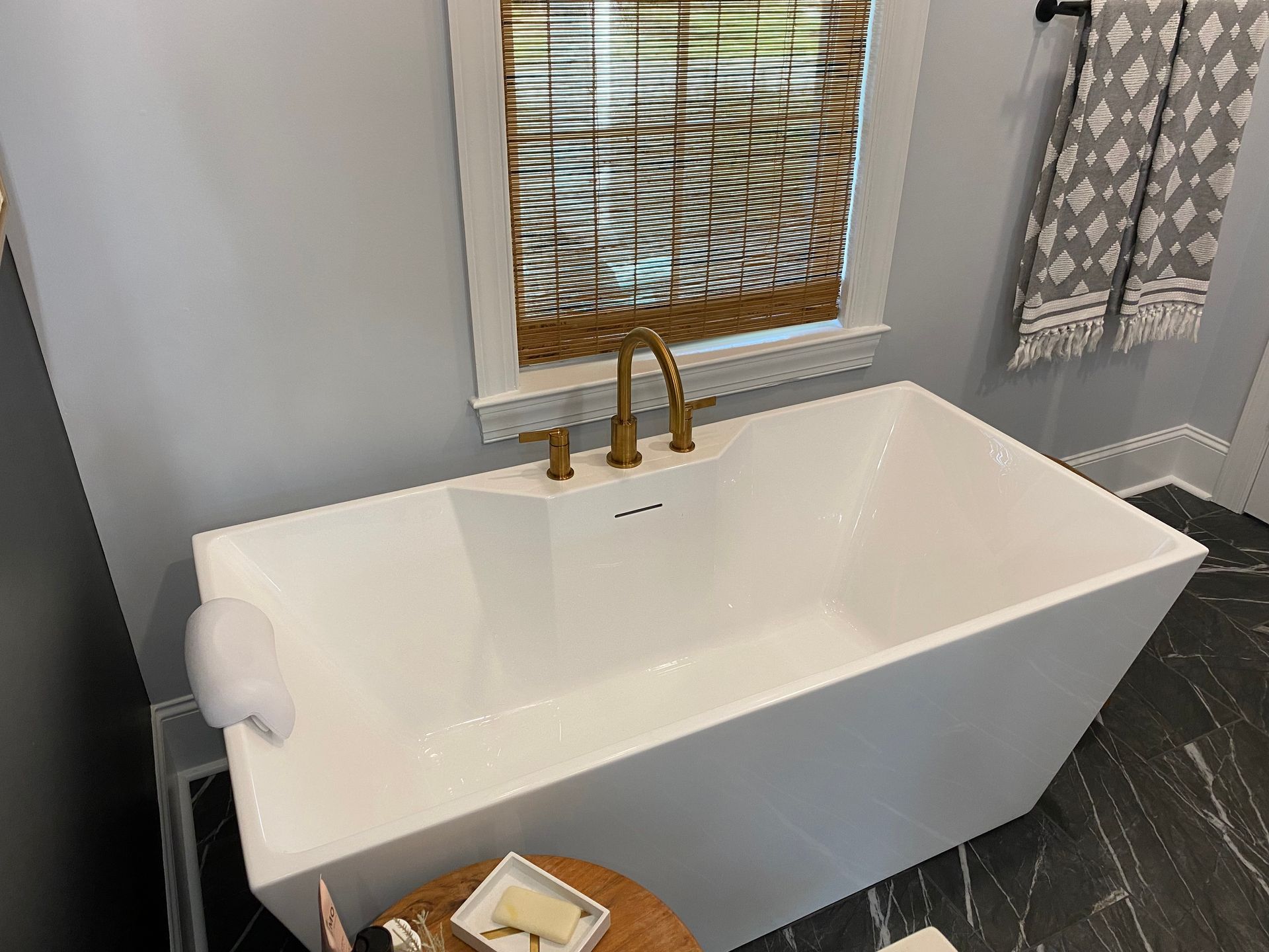 Rectangular free-standing soaker tub with gold deck mount filler valve.