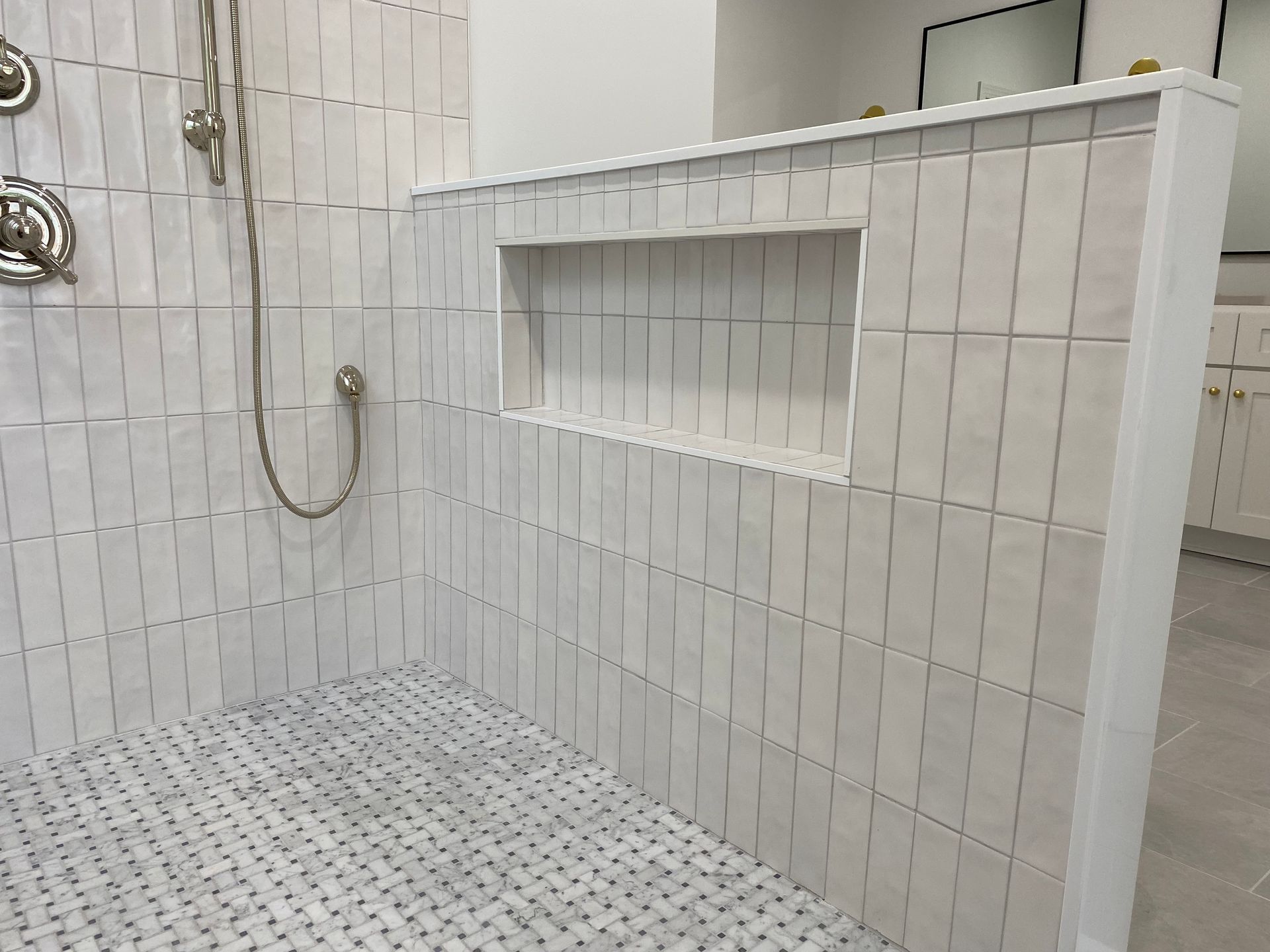Oversized, hidden wall niche in white vertical tile shower.