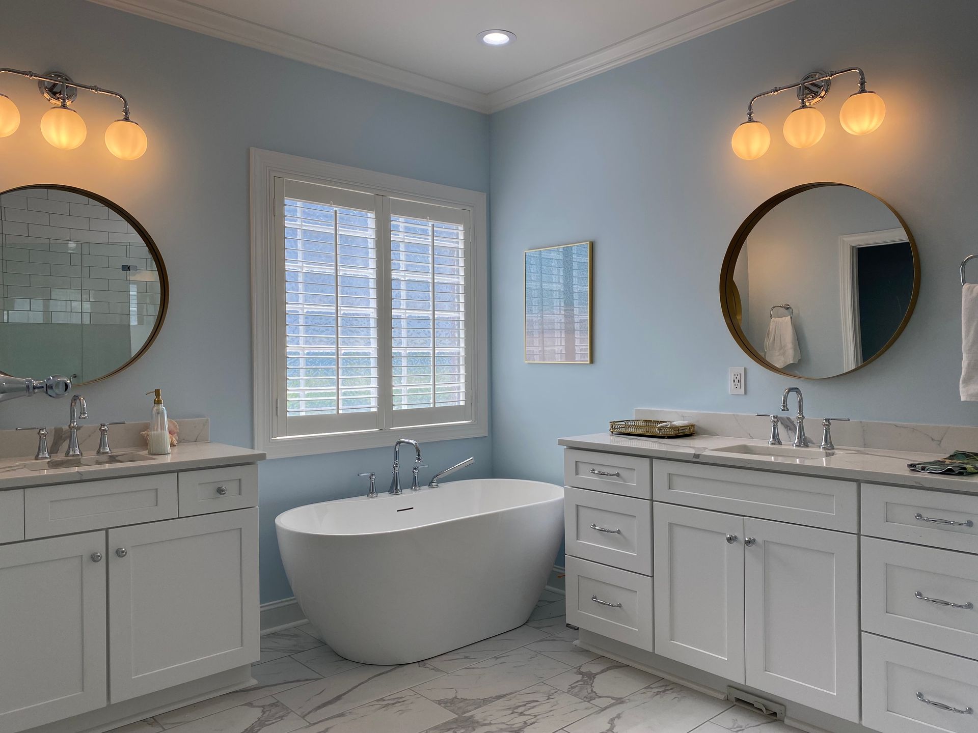 Separate his and hers double vanity with oval soaker tub in the middle.