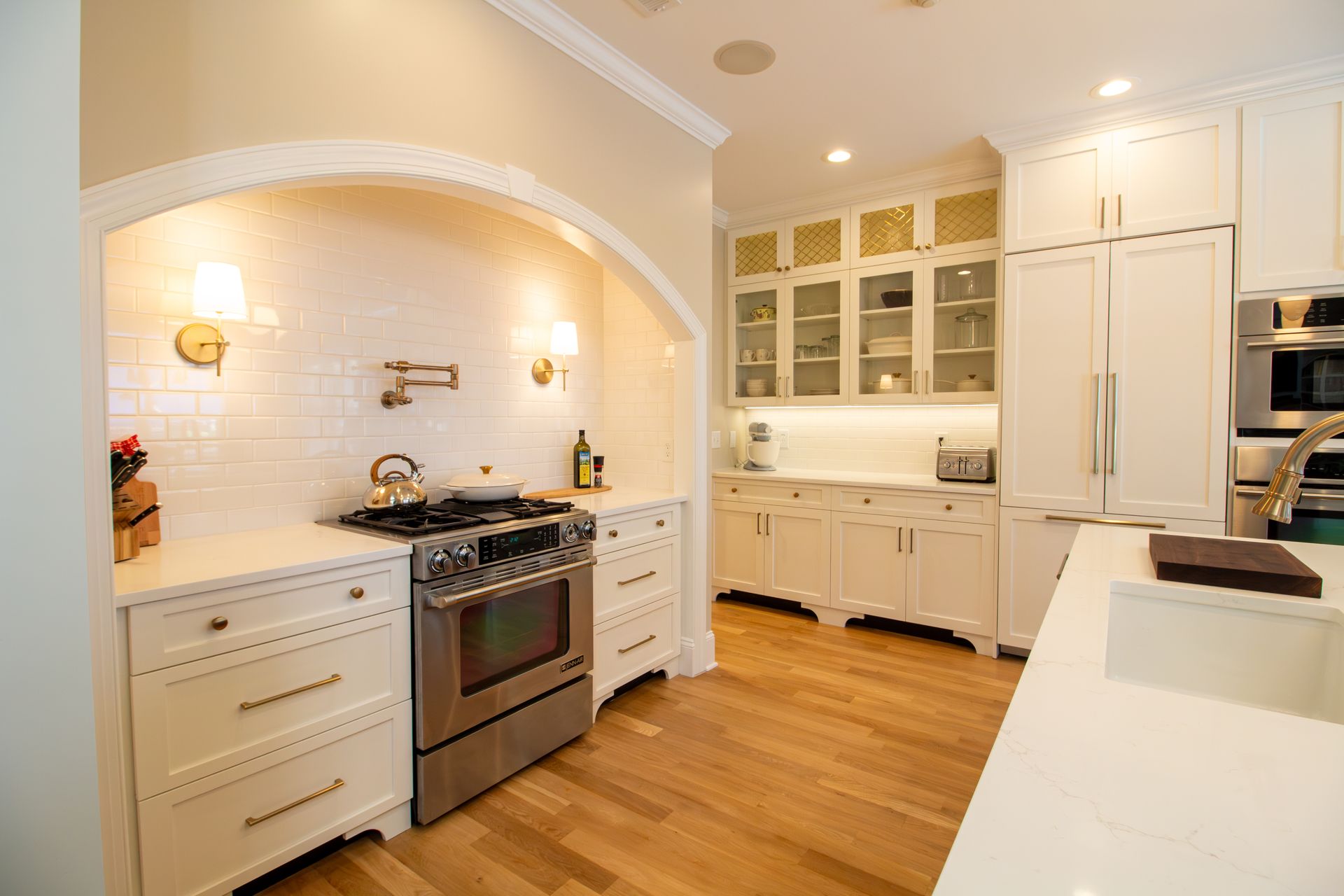 Warm and cozy kitchen with cooking alcove, hidden cabinet paneled refrigerator, and gold hardware and fixtures.