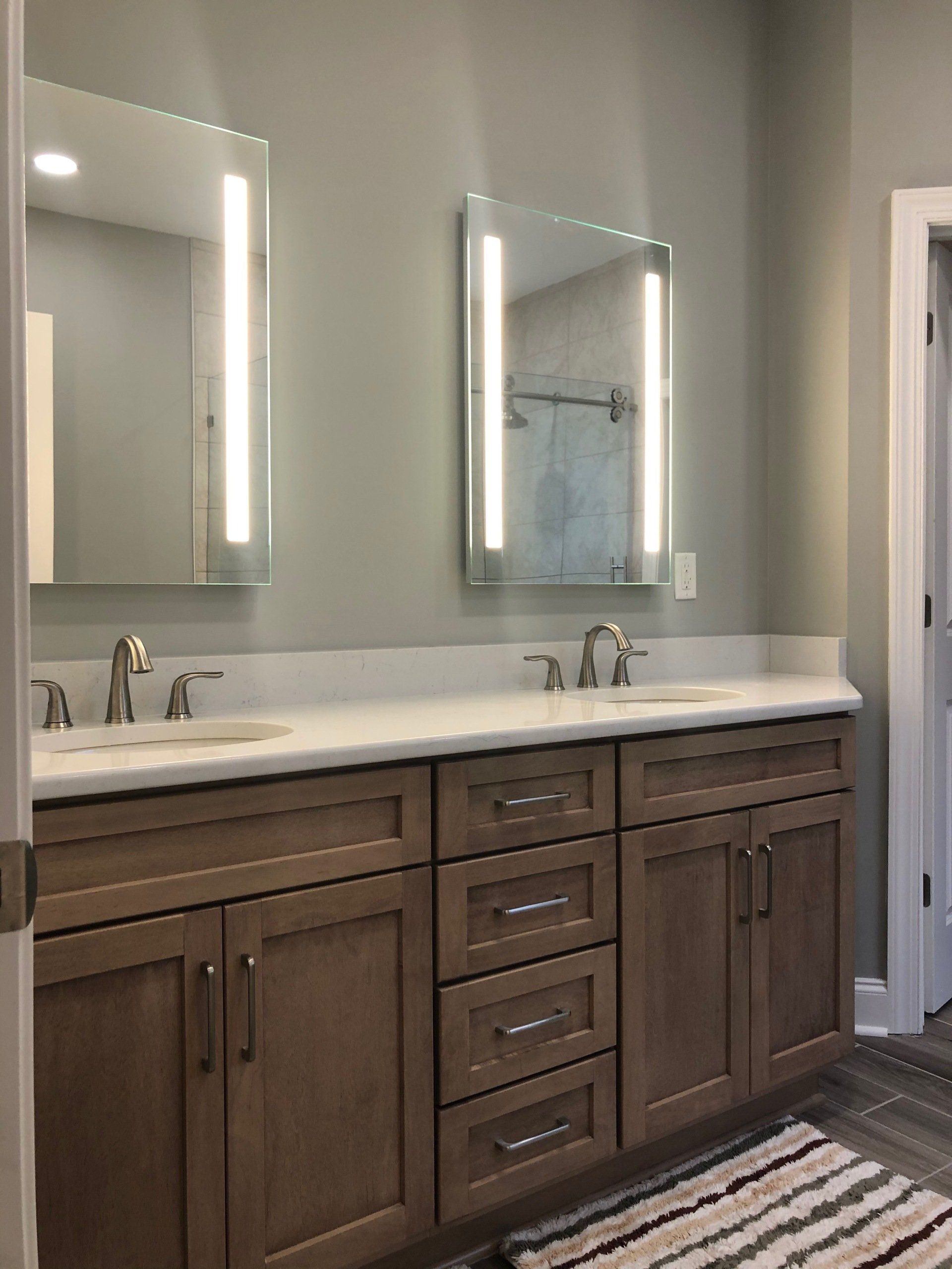 Custom built stained wood cabinet vanity with LED lighted mirrors.
