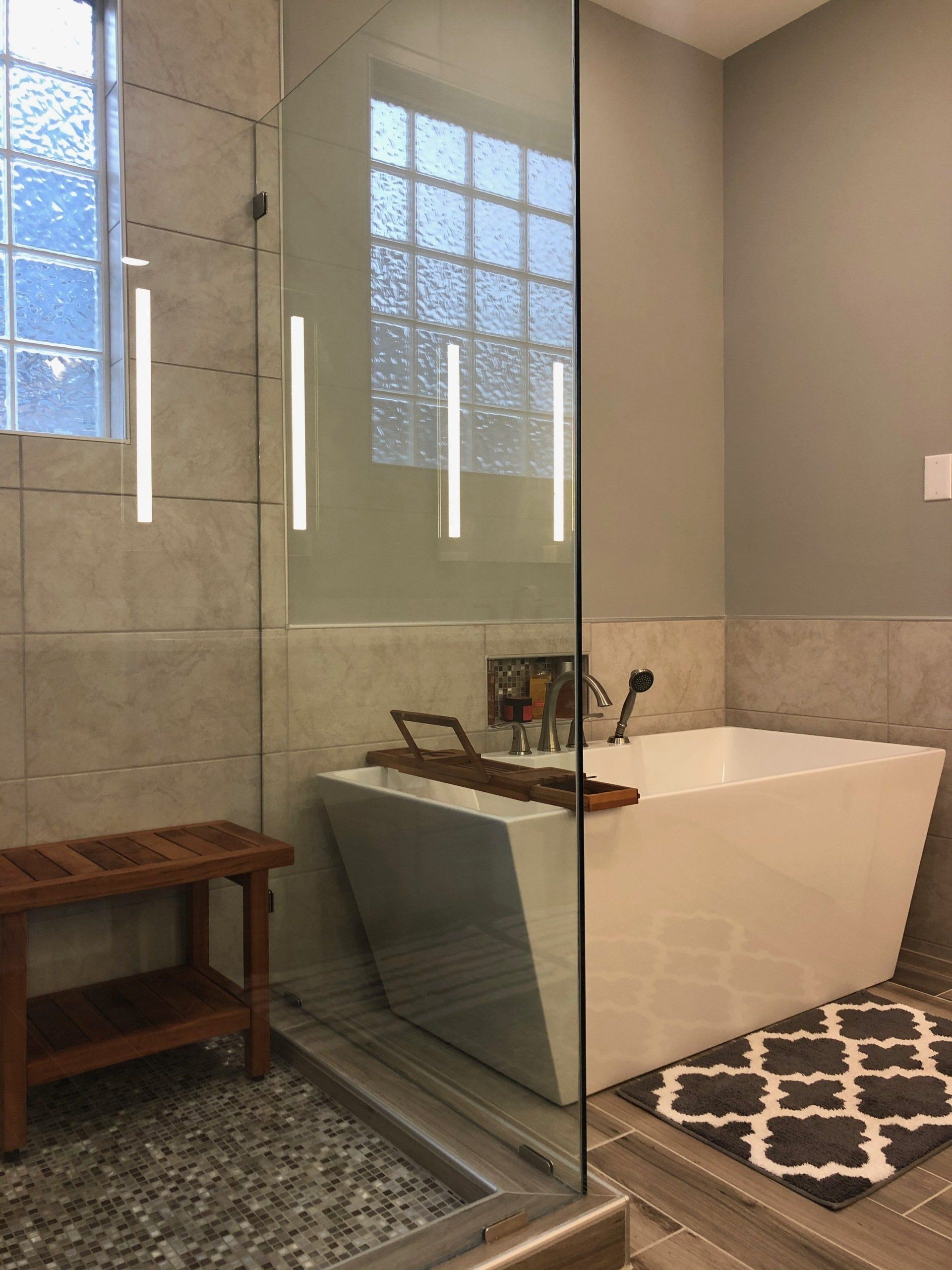 Tile shower with teak wood shower bench and separate free-standing tub with matching teak wood bath caddy.