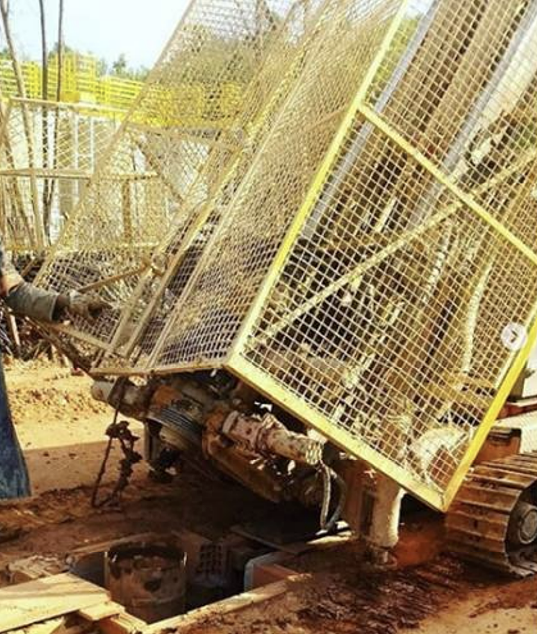 Um homem está trabalhando em uma máquina com uma gaiola amarela ao redor dela