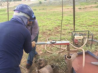 Dois homens estão trabalhando em uma máquina em um campo.