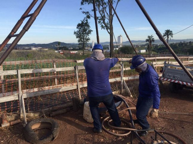 Dois homens estão trabalhando em um canteiro de obras com uma cerca ao fundo