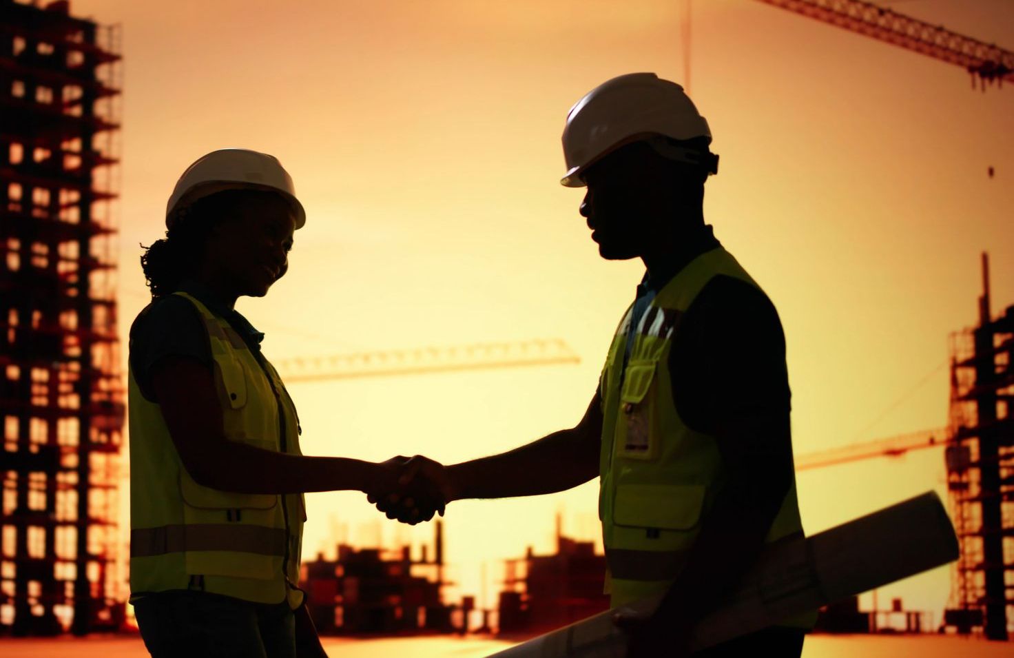 Um homem e uma mulher apertando as mãos em um canteiro de obras