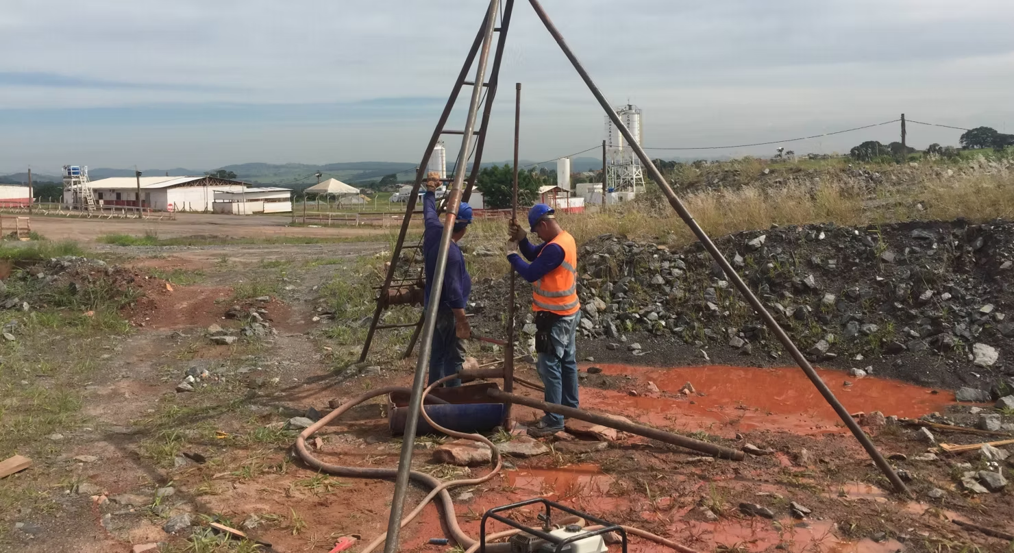 Dois homens estão trabalhando em uma furadeira em um campo.