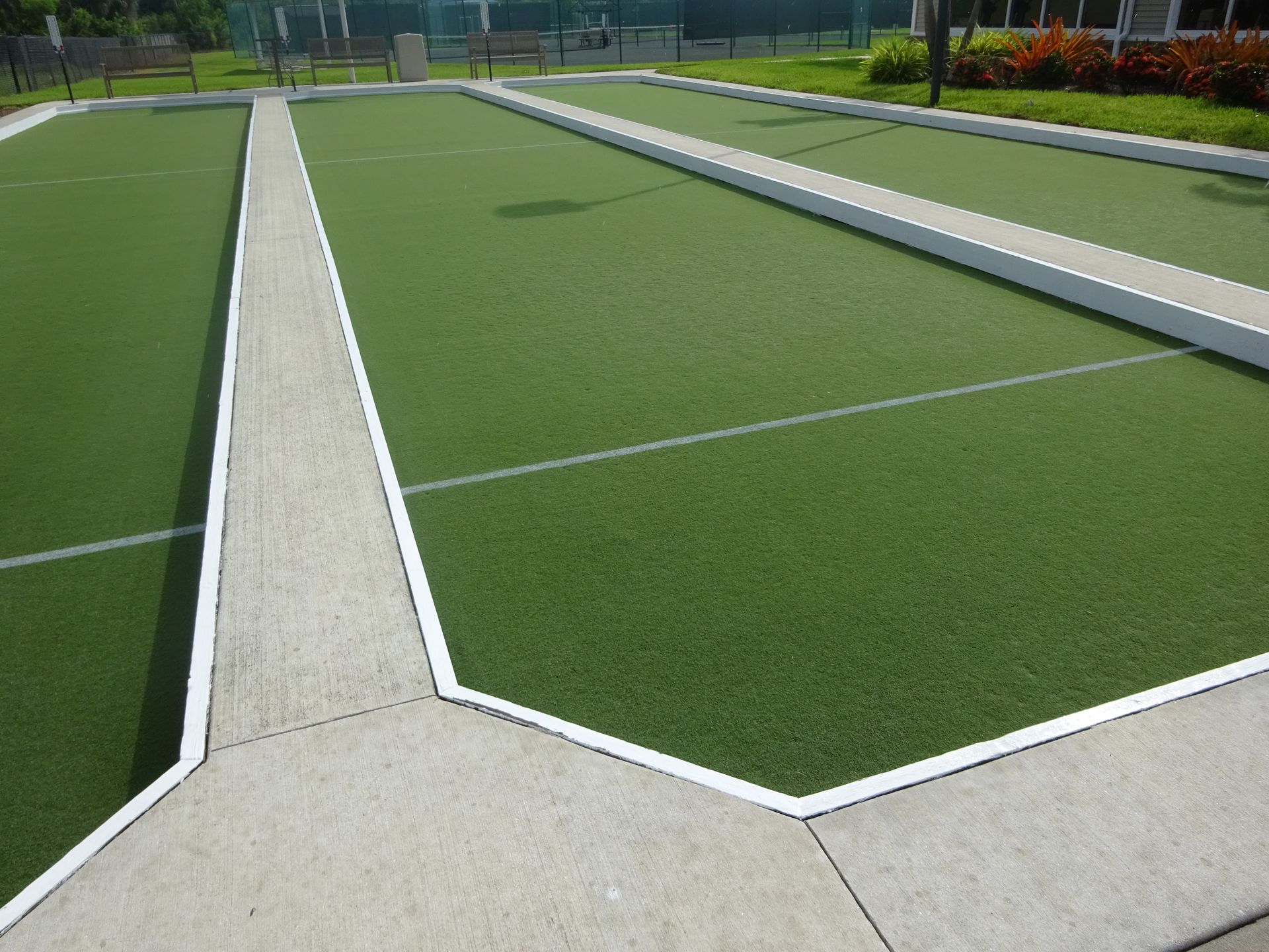 Person rolling out a roll of green artificial turf on a sunny day.
