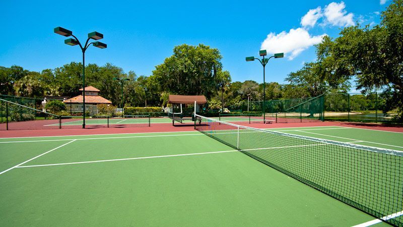 Roll of black material on installed artificial turf, with worker installing more turf in the background.