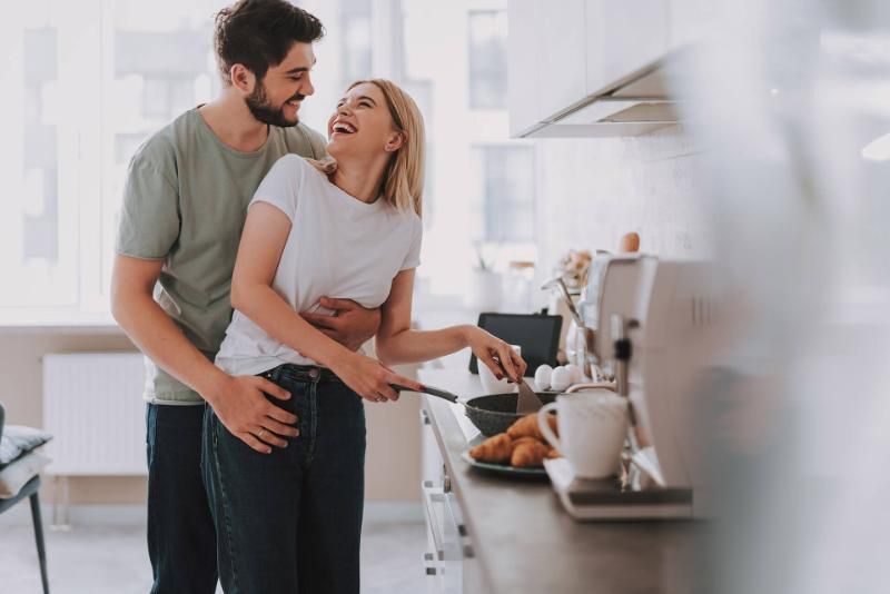 un uomo abbraccia una donna mentre cucina in cucina
