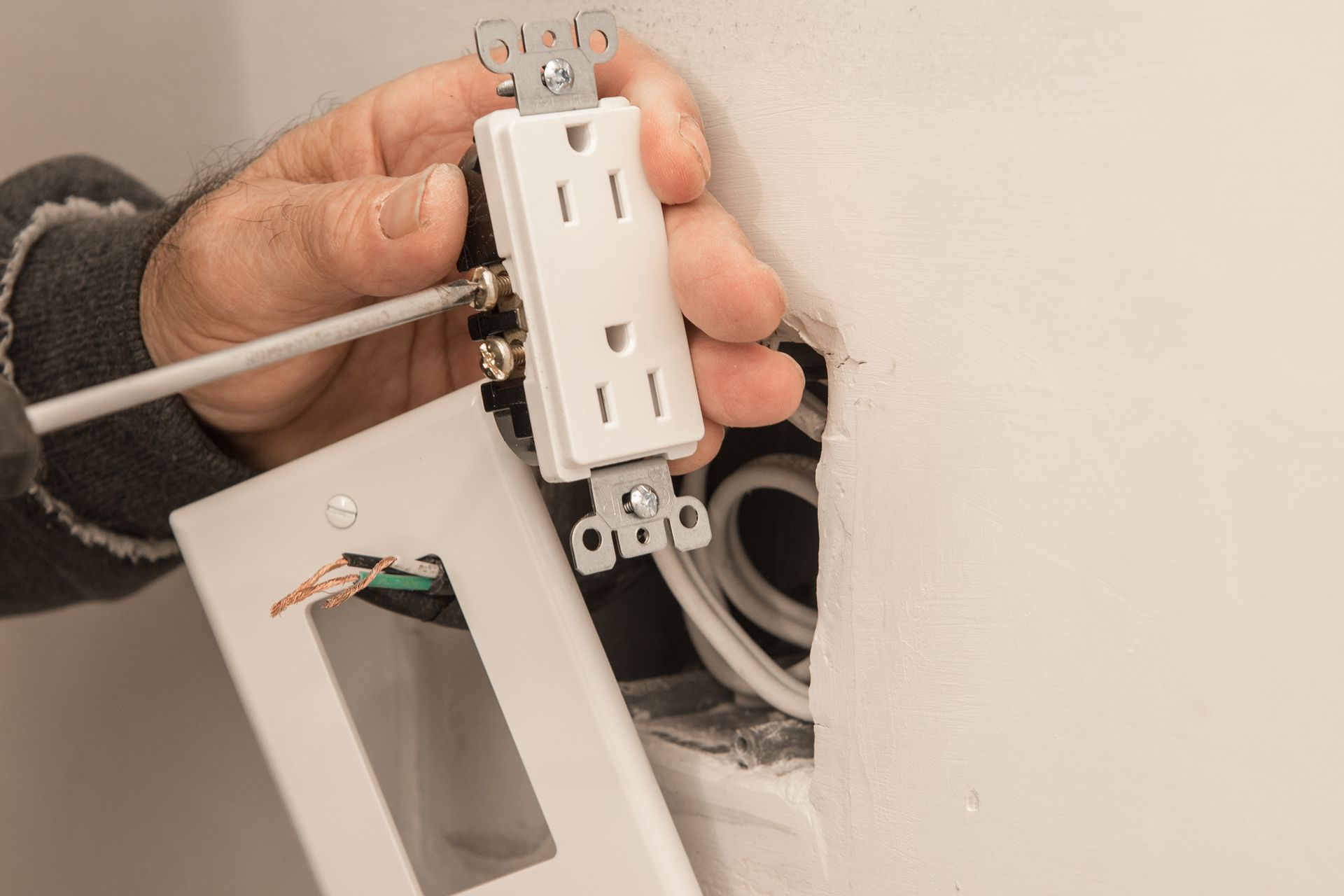 A person is installing an electrical outlet in a wall.