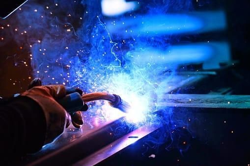 A Person Is Welding a Piece of Metal in A Factory — Mingweld Fabrication in Bungalow, QLD