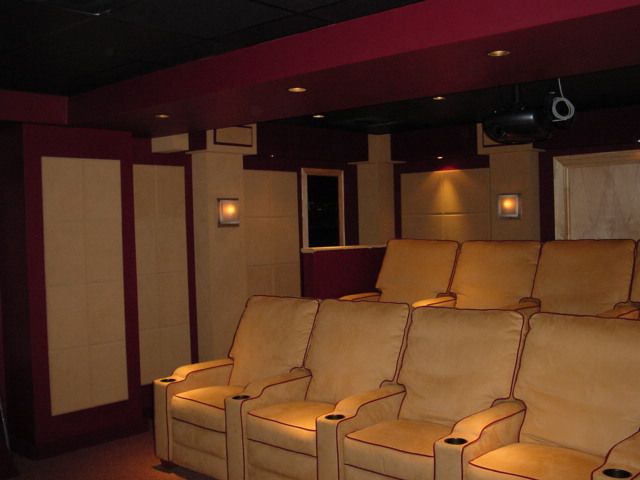 A row of chairs in a theater with a projector hanging from the ceiling