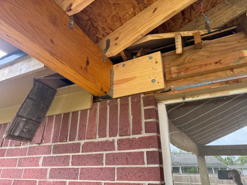 Brick exterior wall supports a wooden overhang, with visible framing and roof.