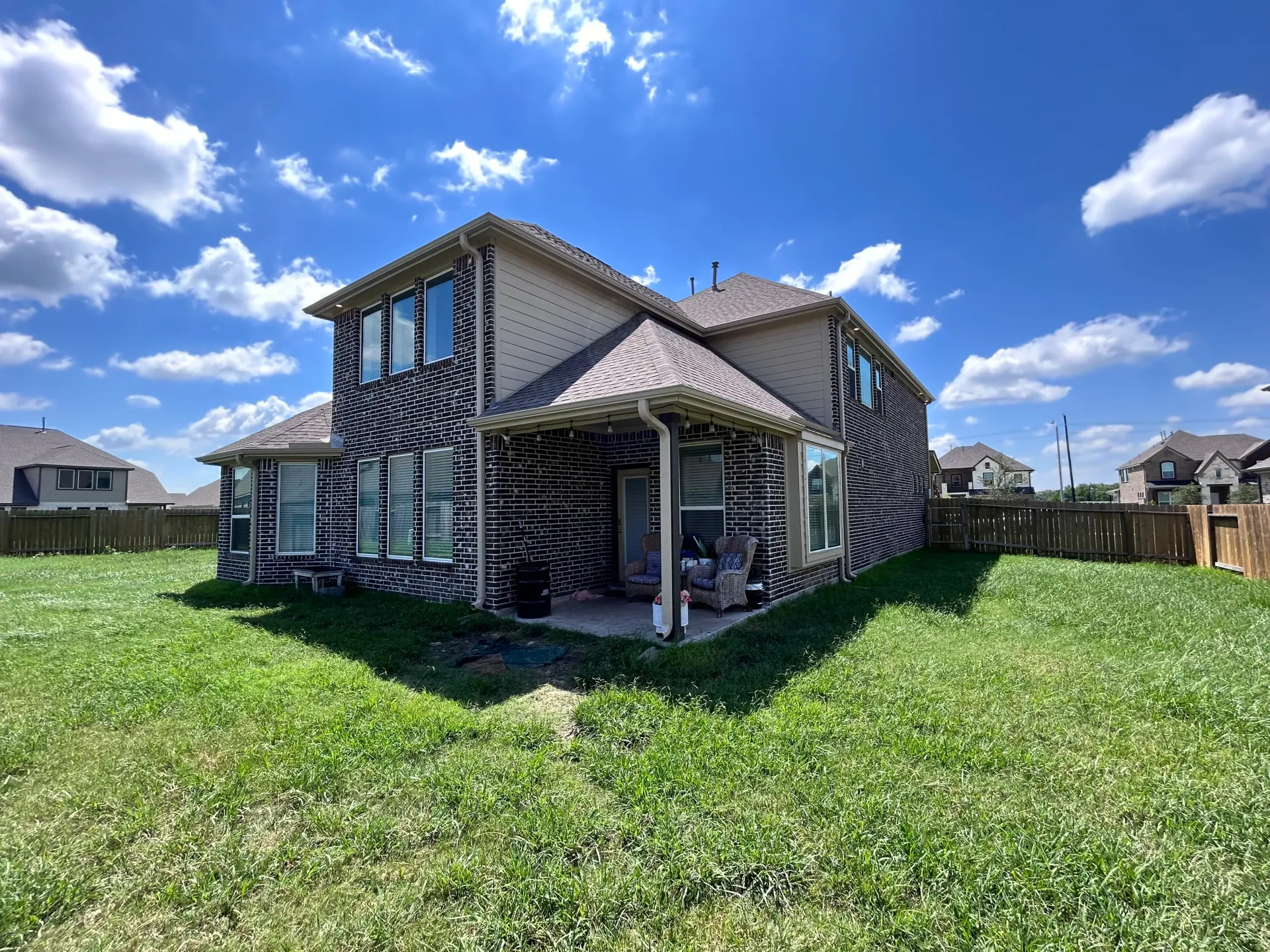 Two-story house with black and white patterns on the exterior, in a grassy backyard under a blue sky.
