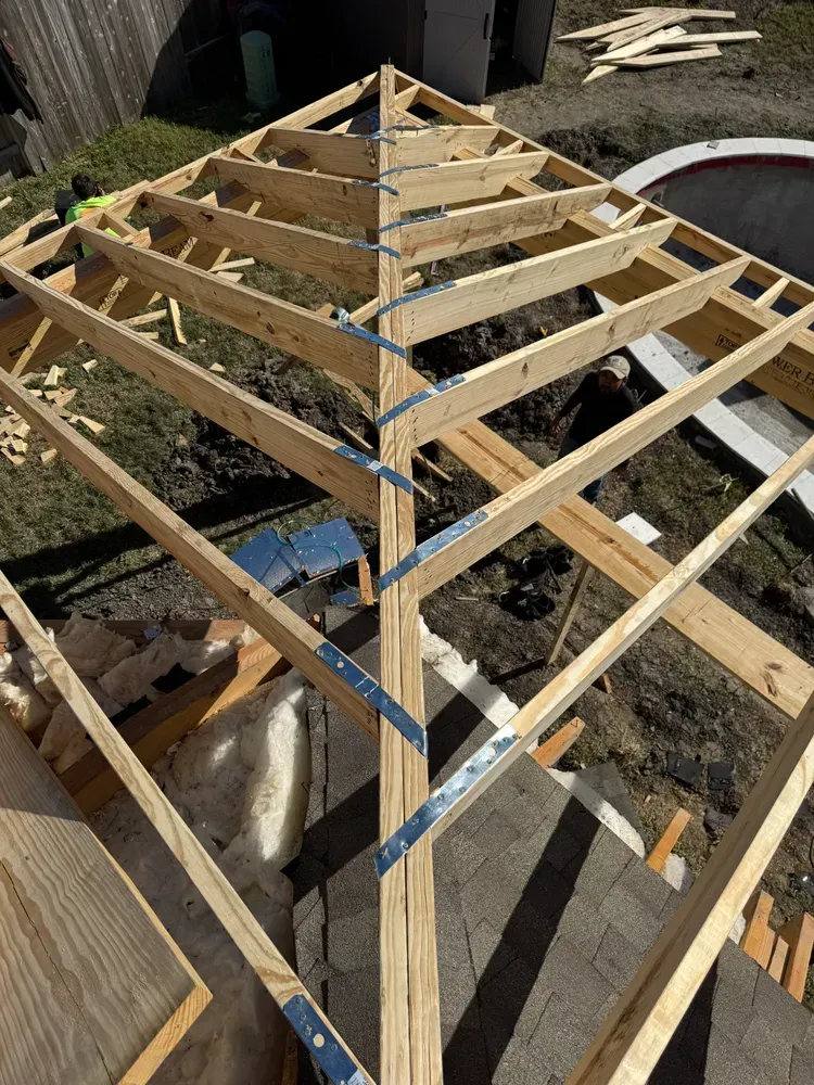 Wooden gazebo roof under construction, frame and metal brackets.