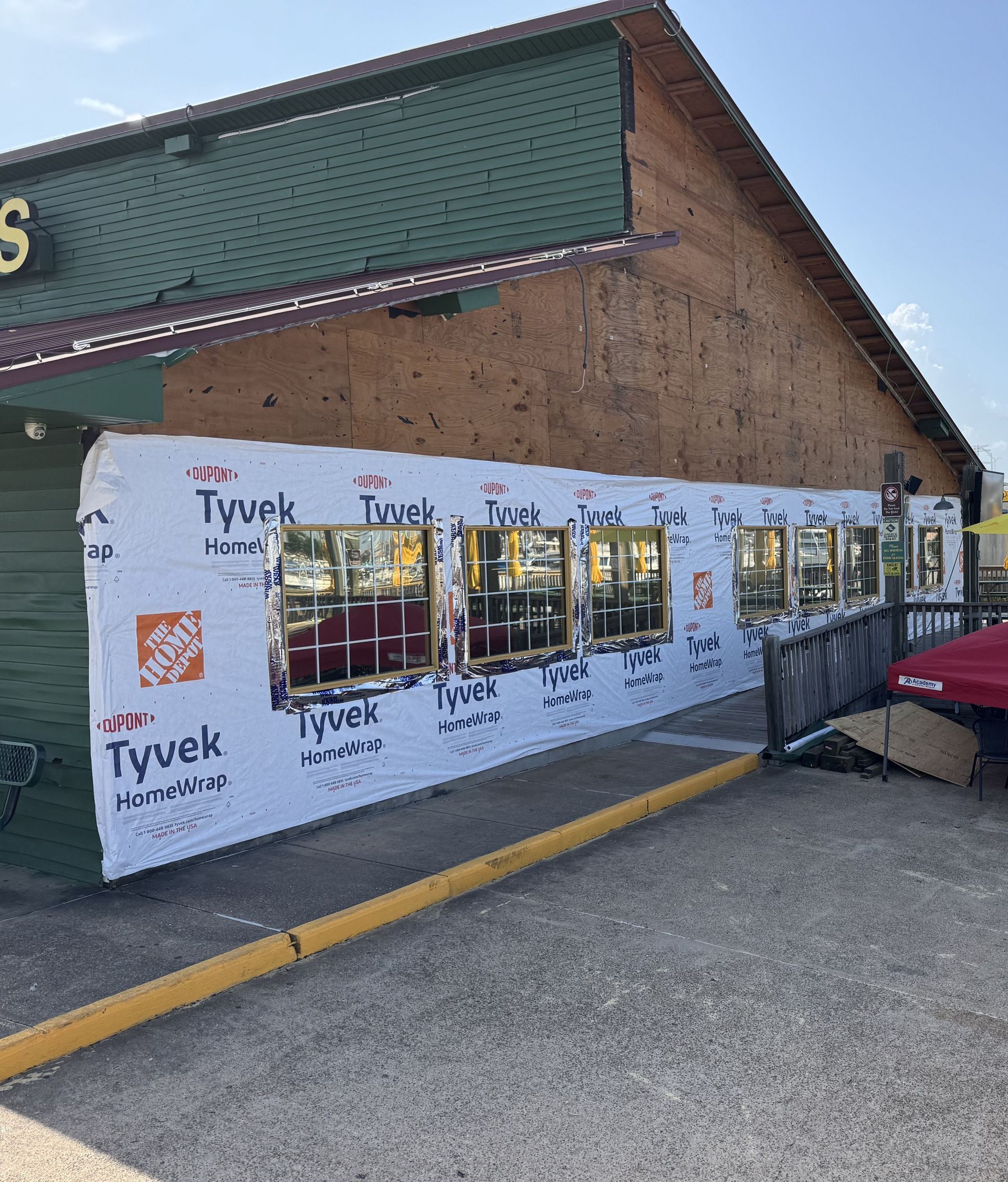 Building under construction with Tyvek wrap, windows, and a ramp.