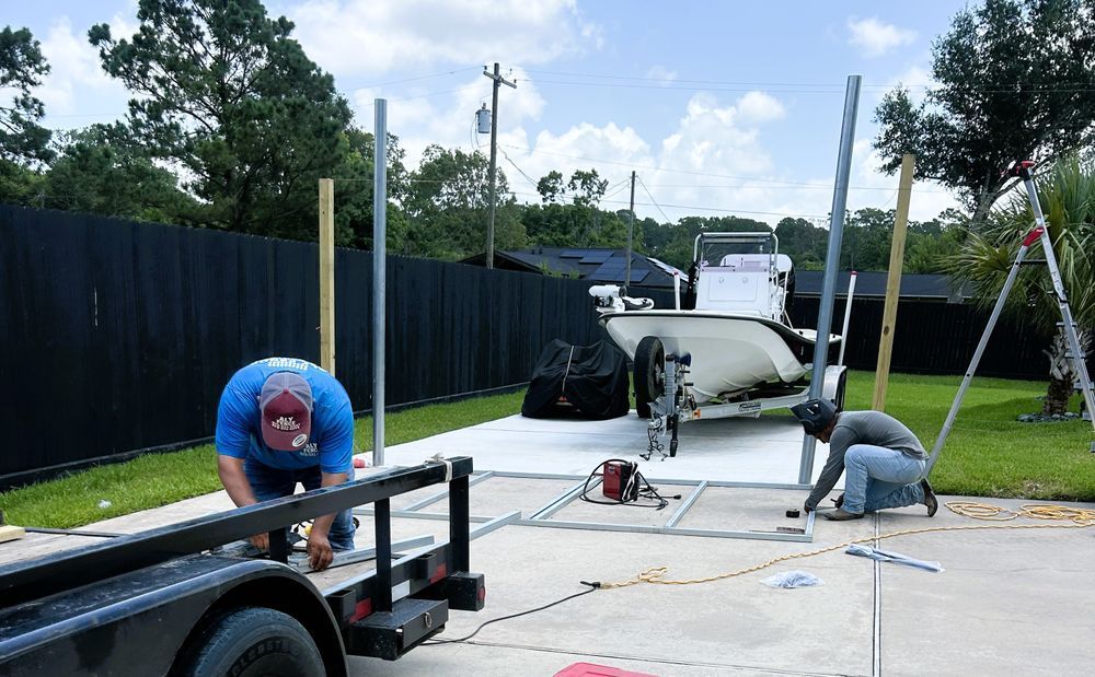 Two men building a metal frame structure on a concrete pad, a boat nearby.