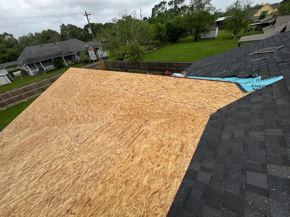 New plywood sheathing on a residential roof with asphalt shingles partially installed.